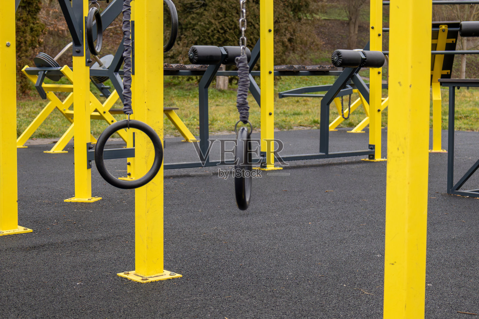 明亮的黄色健身器材摆放在健身区域,展示着公园草地上准备好进行各种锻炼的吊环照片摄影图片
