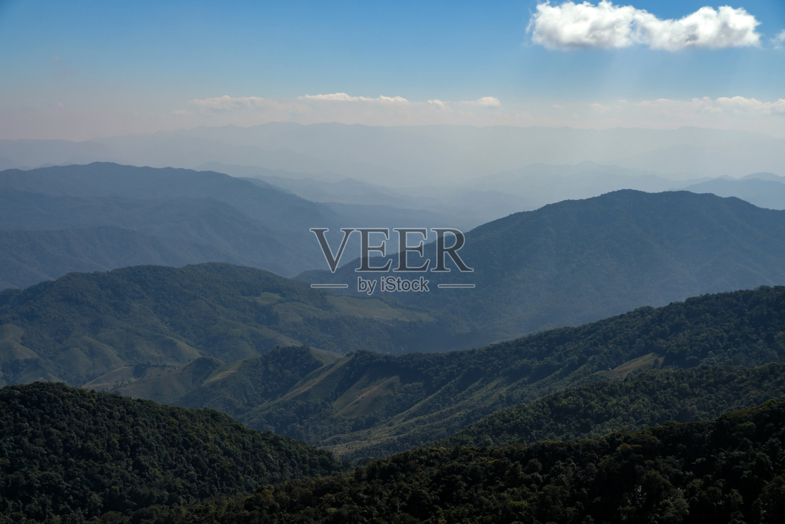 阳光明媚的早晨,晴朗湛蓝的天空中,群山连绵,山谷深邃,飘浮着朵朵白云。照片摄影图片