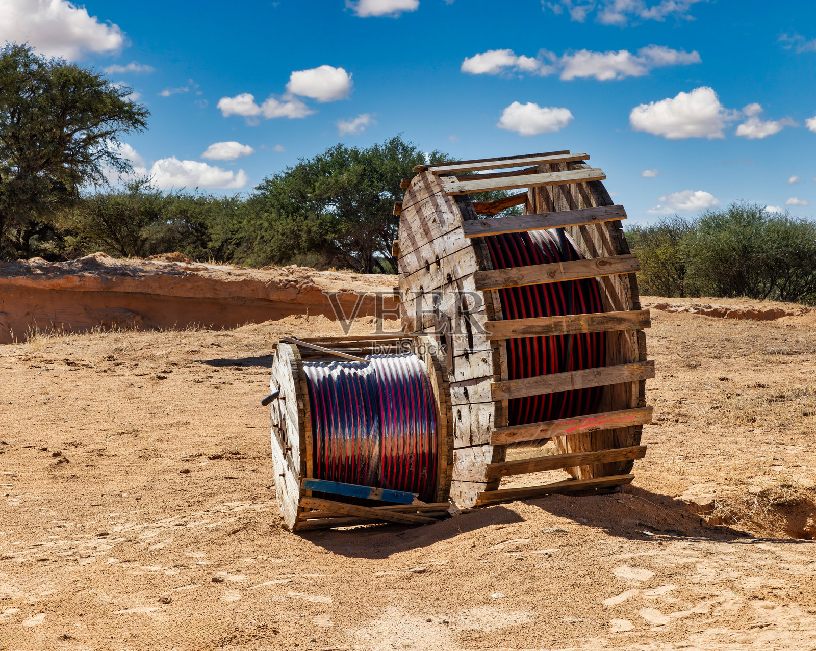 阳光明媚的夏日,建筑工地上有一个巨大的工业电缆卷筒。照片摄影图片