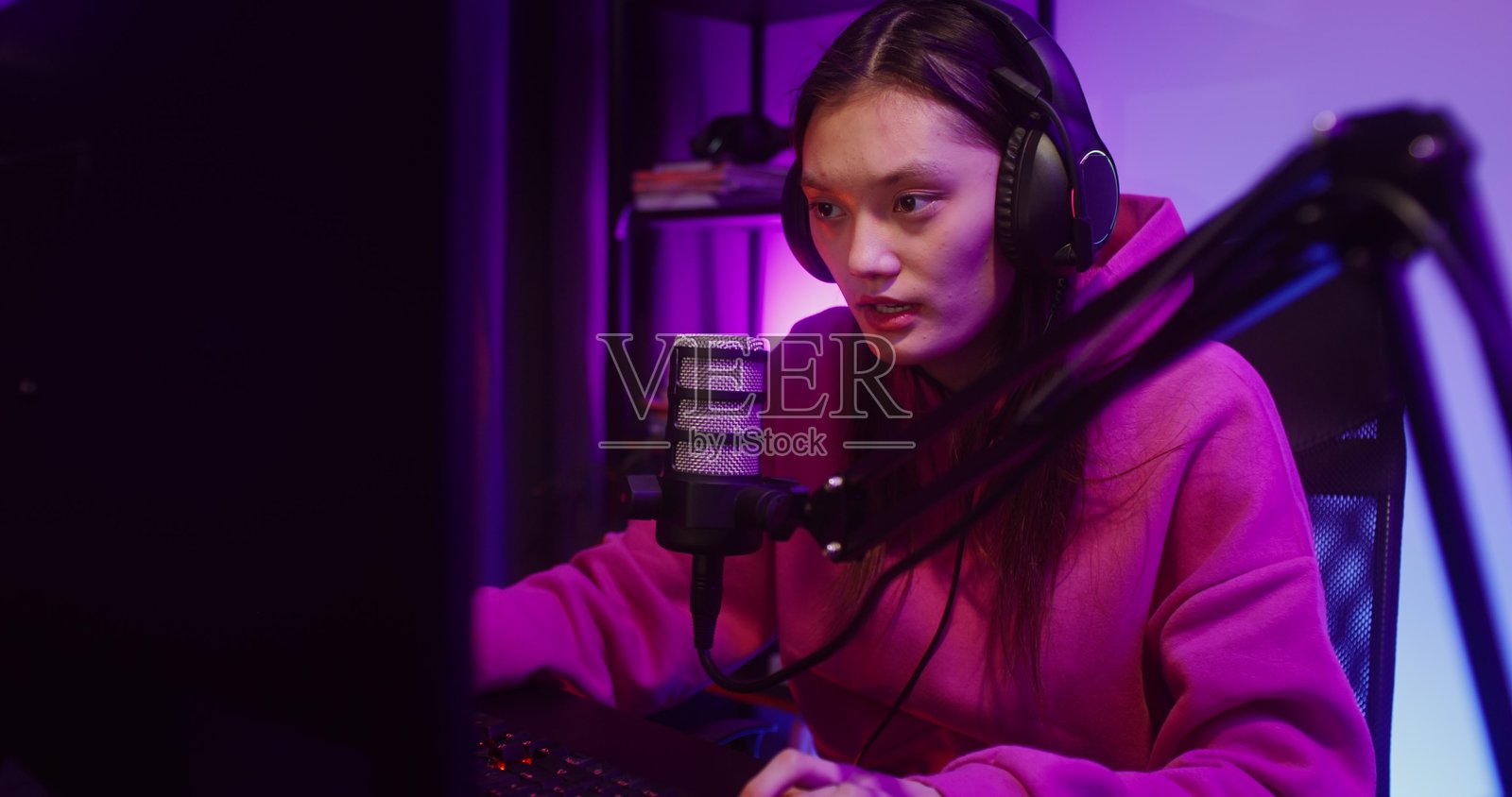 戴着耳机的年轻女子正在对着麦克风讲话 - 游戏照片摄影图片