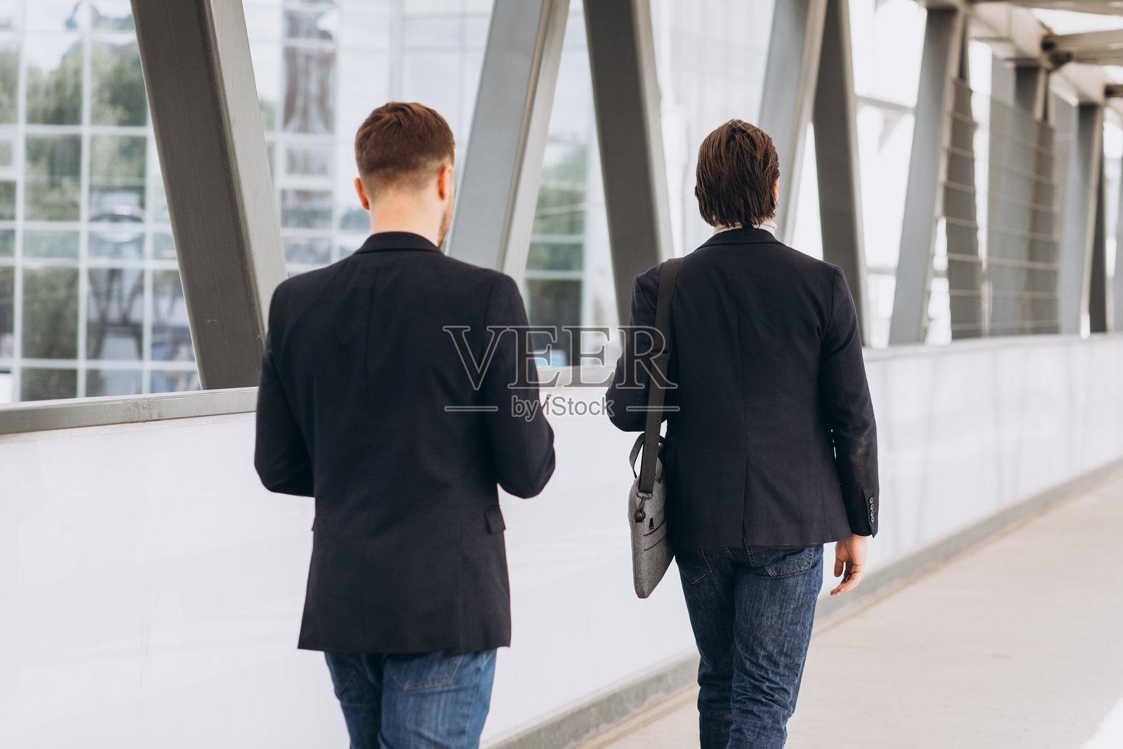 商界人士走在现代办公楼的走廊里,象征着合作、事业和都市的成功照片摄影图片