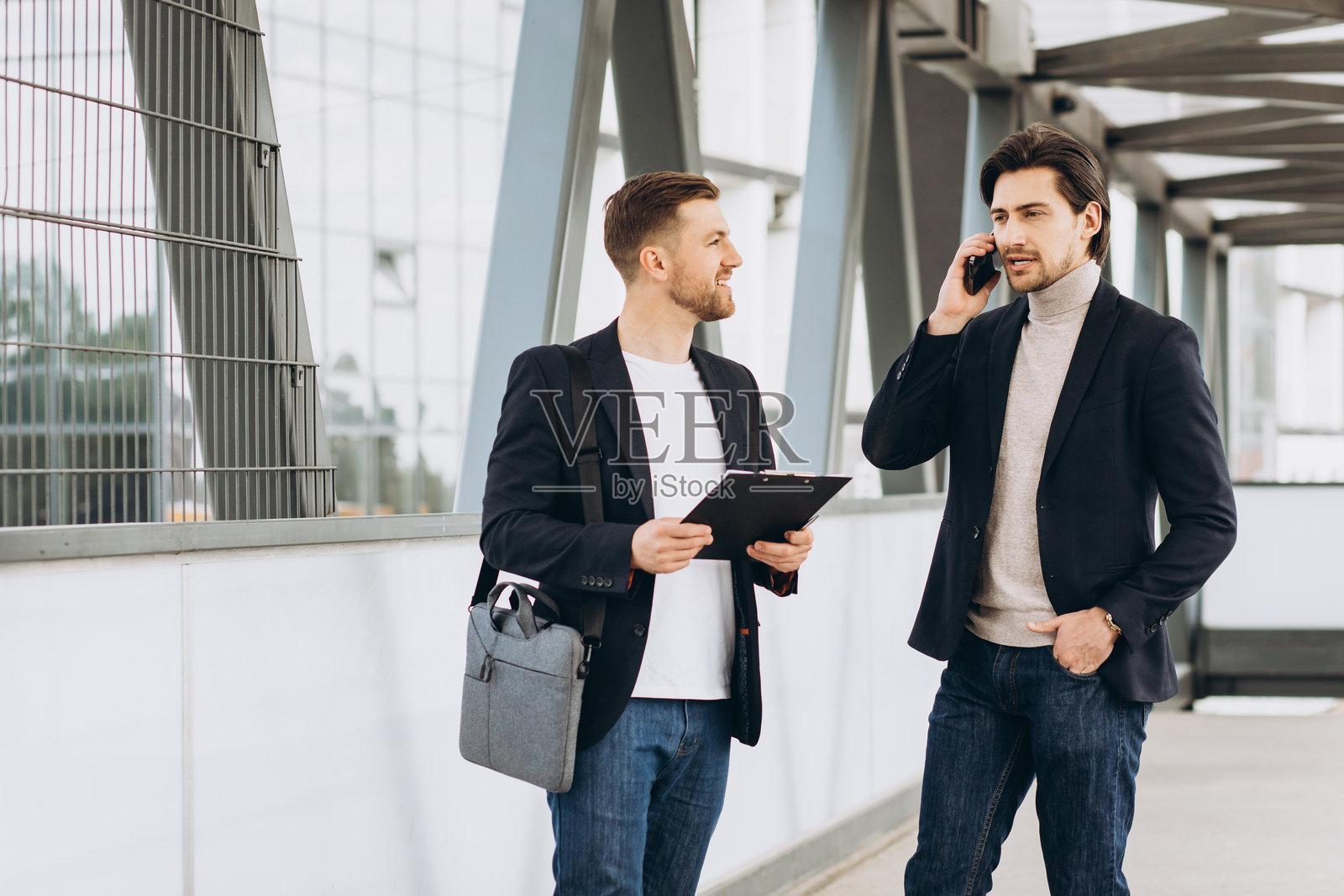 商业伙伴在现代化都市中协作,讨论工作,并使用文件袋和手机通话照片摄影图片