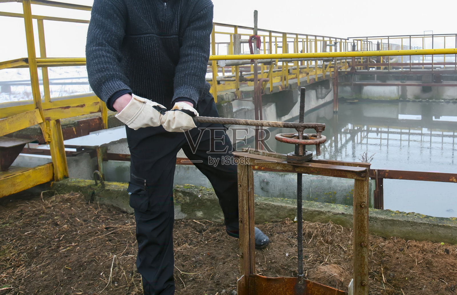 一名工人在冬季的水处理厂操作阀门把手,以完成有效的水务管理任务照片摄影图片
