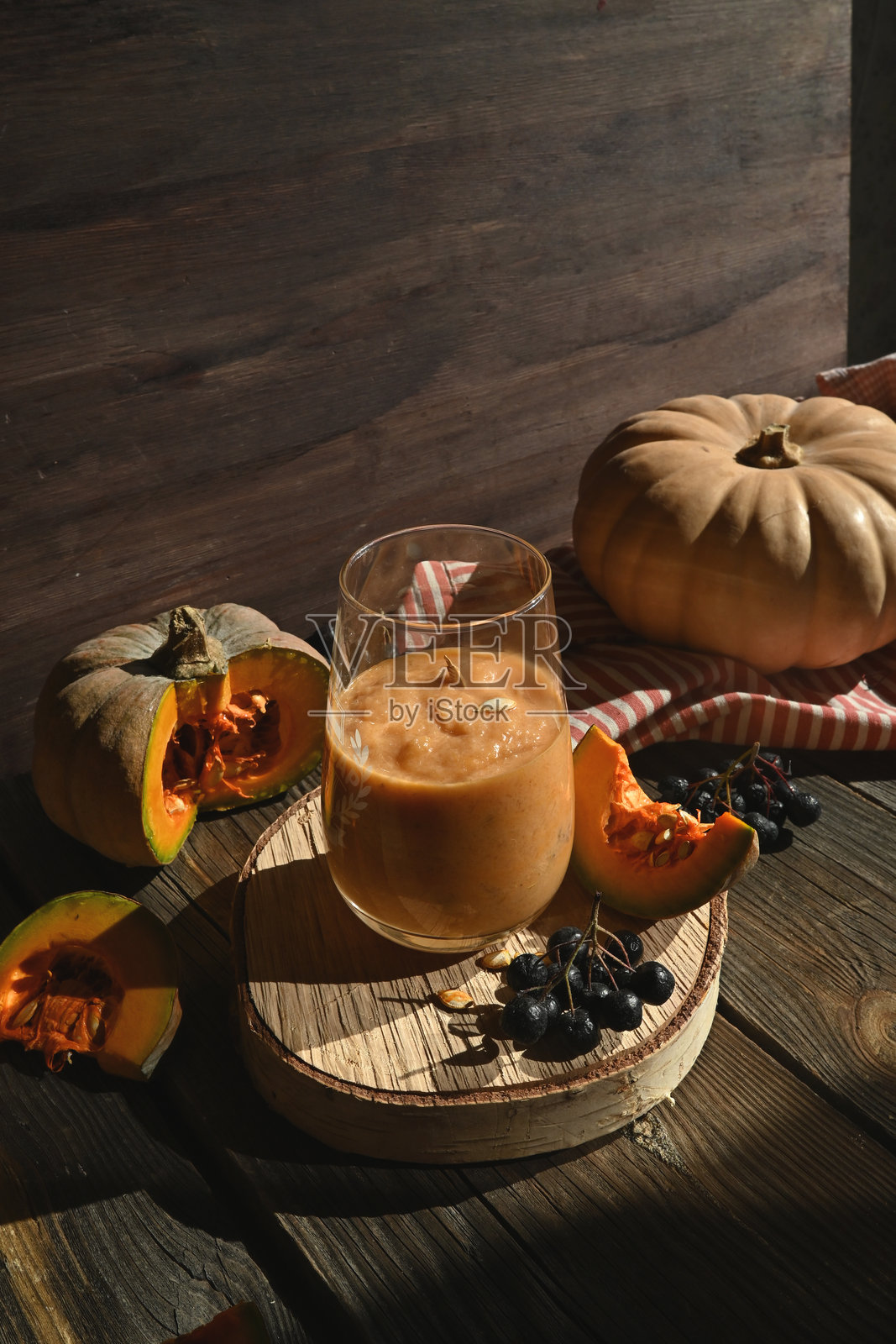 南瓜冰沙是一种健康的饮品,是秋季健康有营养的食物。这是一款在乡村背景上用南瓜和其他蔬菜制成的维生素饮品。照片摄影图片