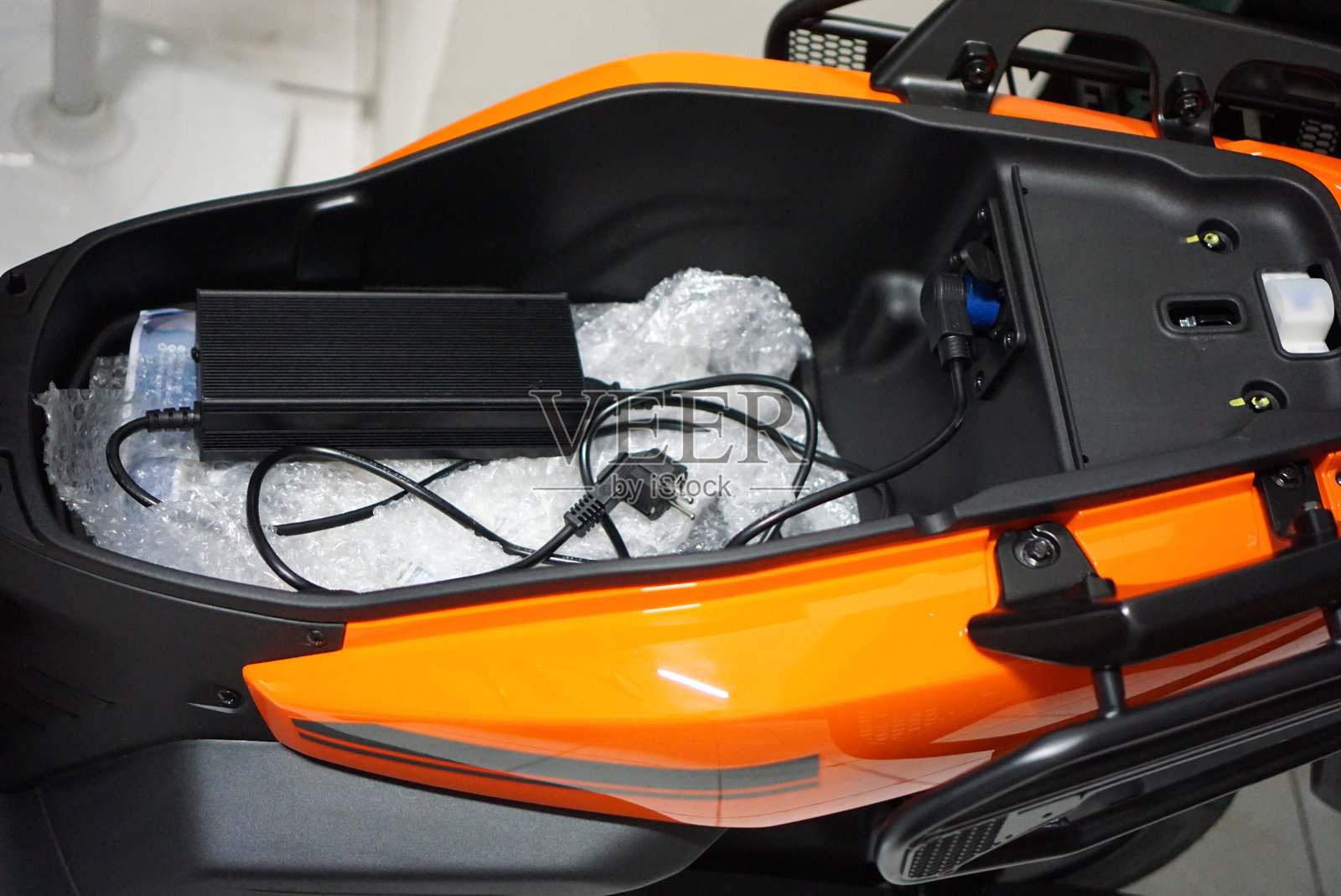 充电器和电池存放在电动滑板车的座椅下方隔间里。照片摄影图片