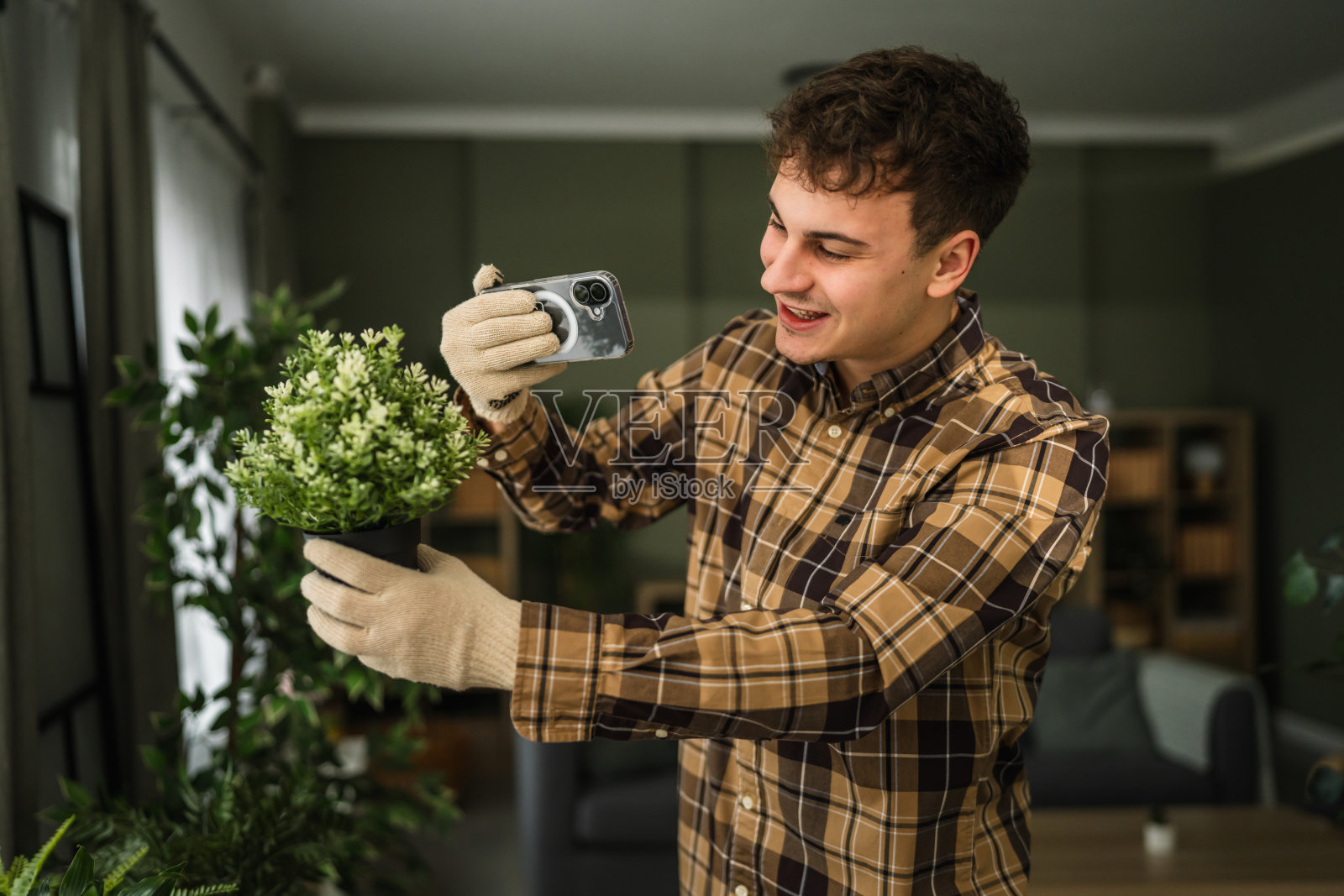 年轻男子用智能手机拍摄室内植物以创作内容照片摄影图片