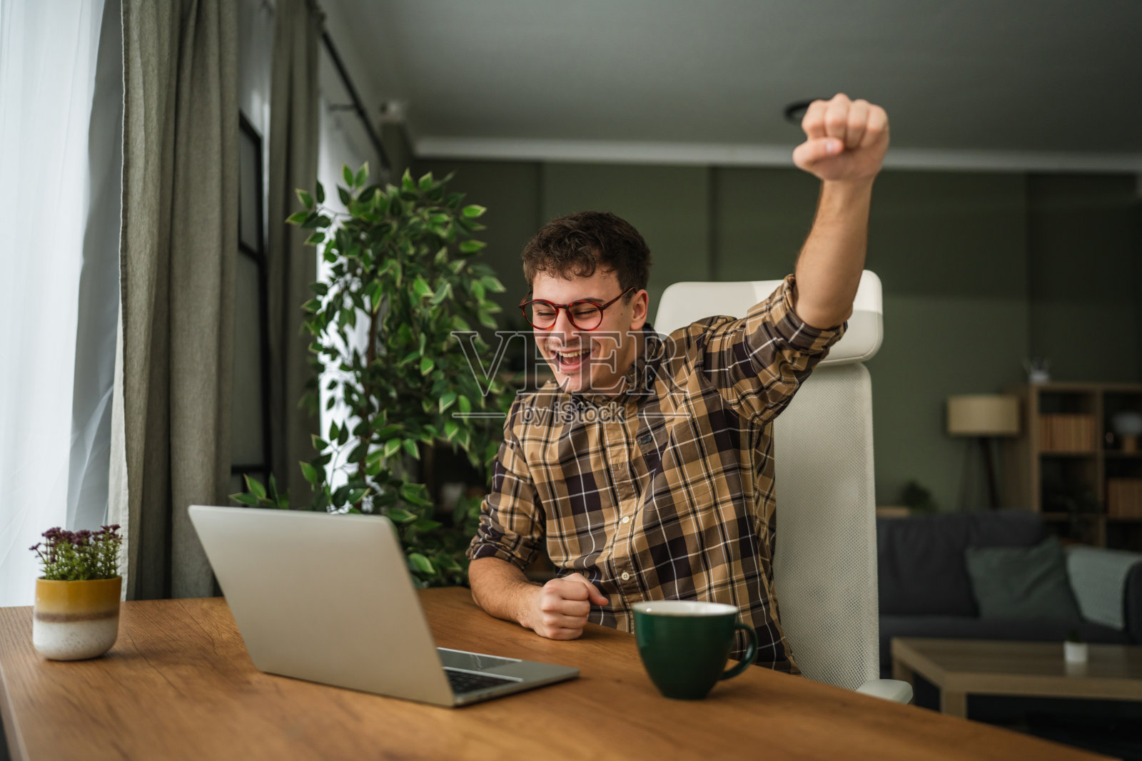 年轻男子在家中办公室庆祝成功照片摄影图片