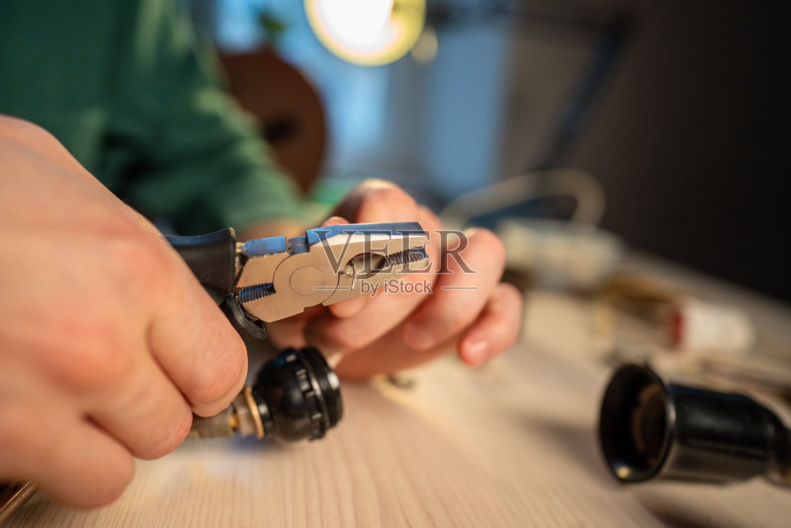 男人在家里的工作室,用钳子修理旧灯泡插座灯的电线照片摄影图片