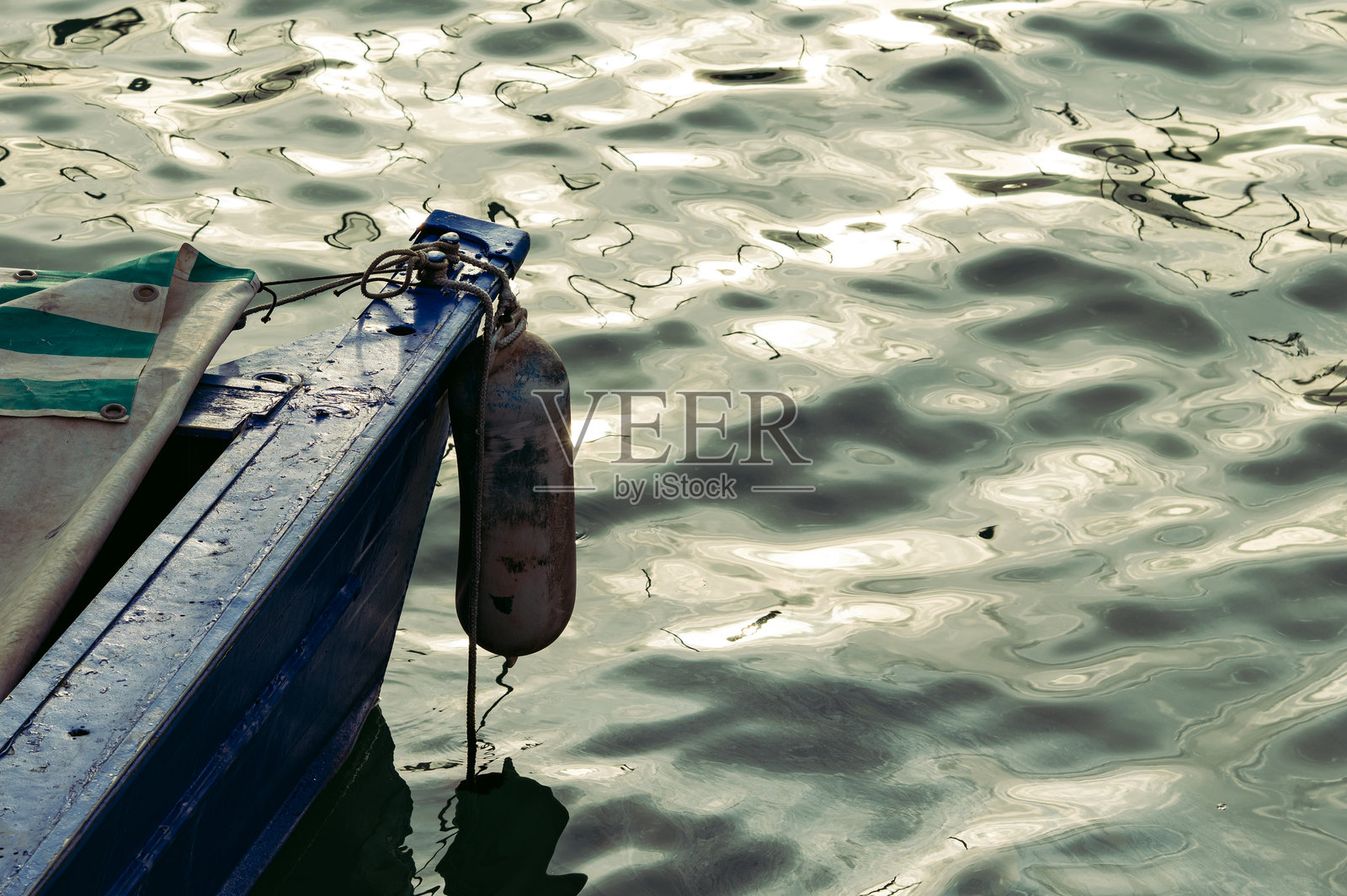 停泊在平静水面上的渔船船头,水面有倒影照片摄影图片