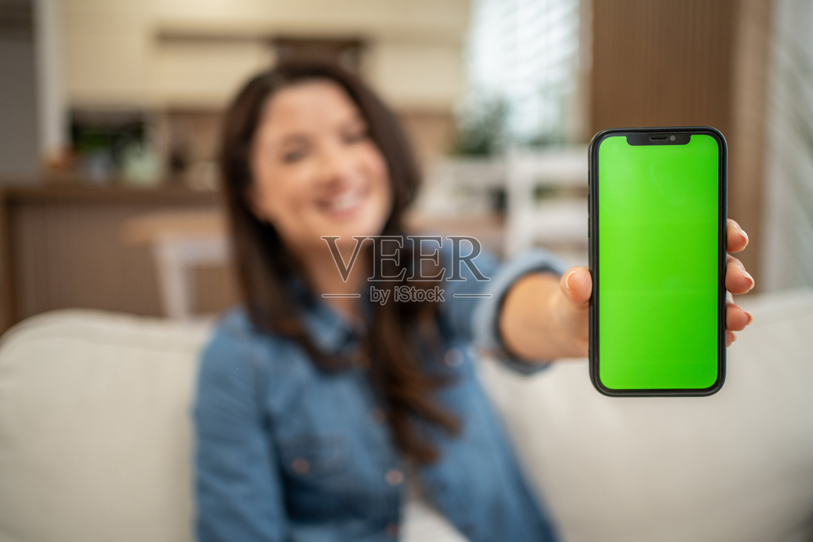 女子手持带有显示应用界面的绿屏的智能手机照片摄影图片