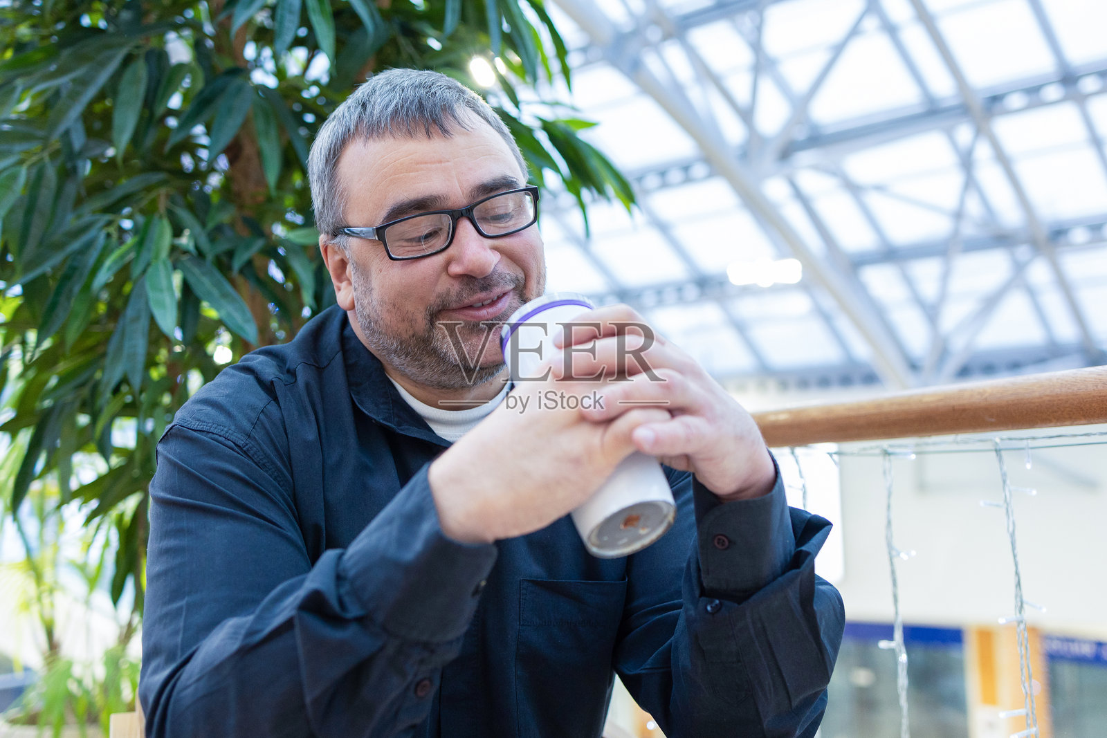 现代商场室内,一名男子手持外卖咖啡照片摄影图片