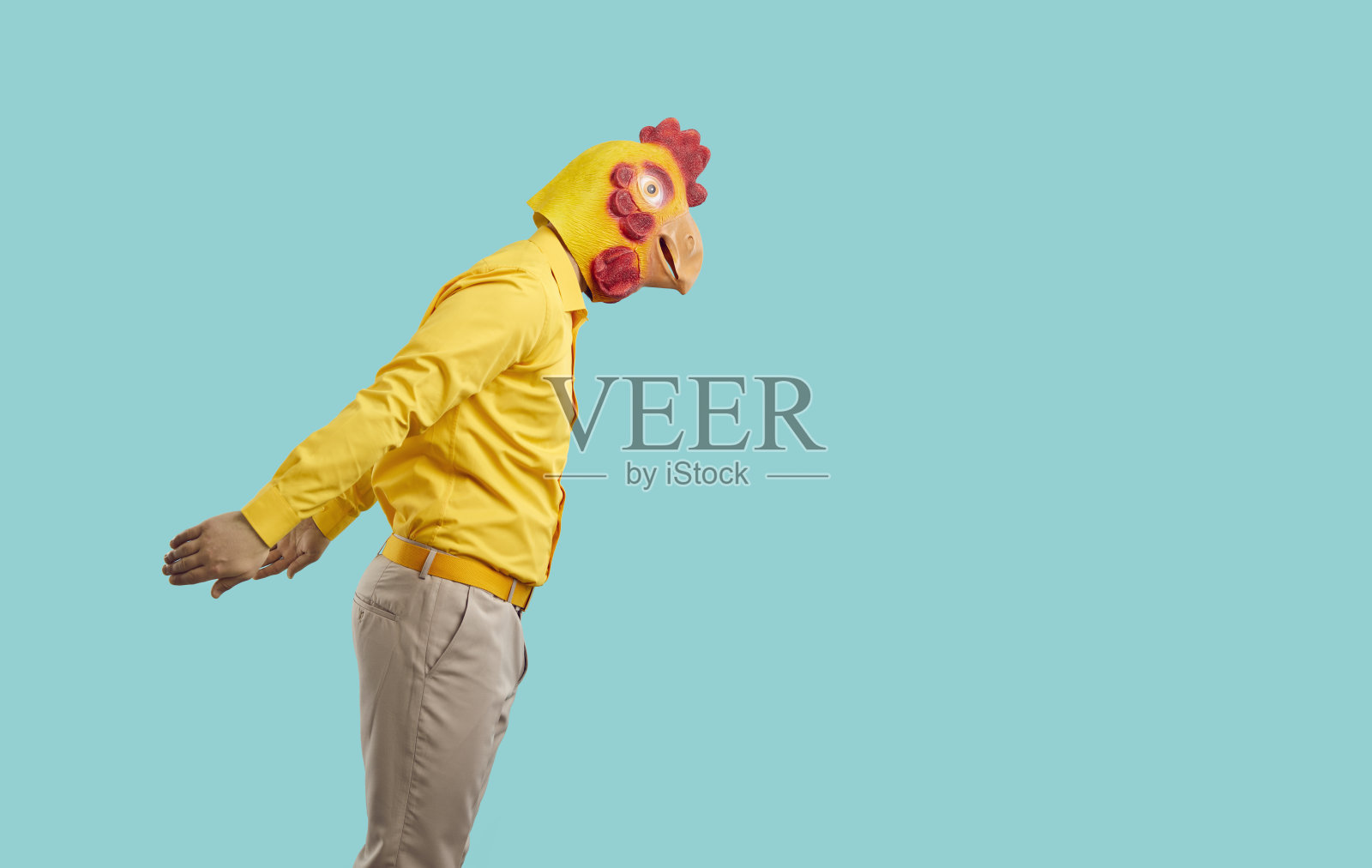 穿着衣服、戴着滑稽鸡头面具的男人侧身准备跳入水中照片摄影图片