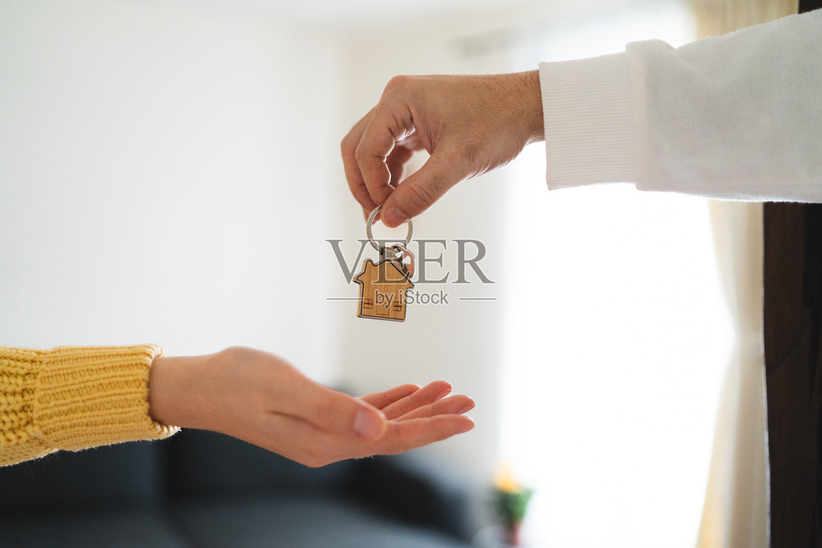 在明亮的新家交换钥匙的双手照片摄影图片