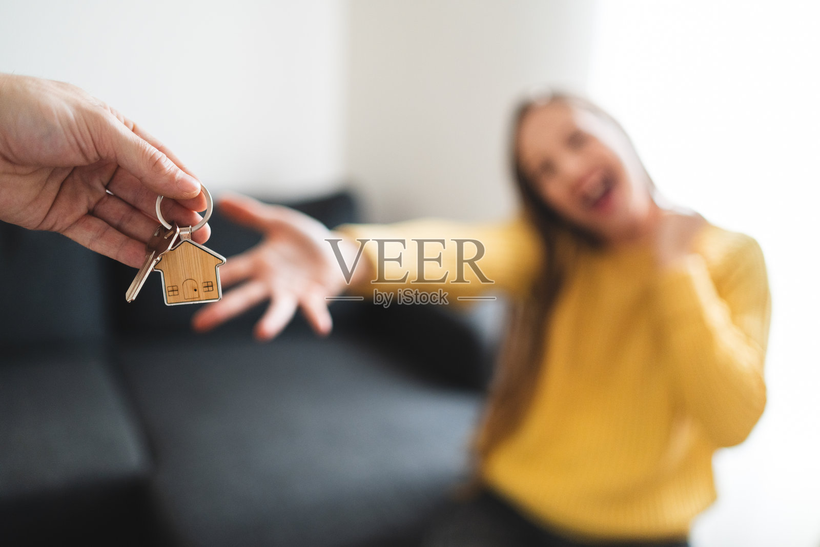 沙发上,一只手将钥匙递给一位女性,钥匙是焦点照片摄影图片