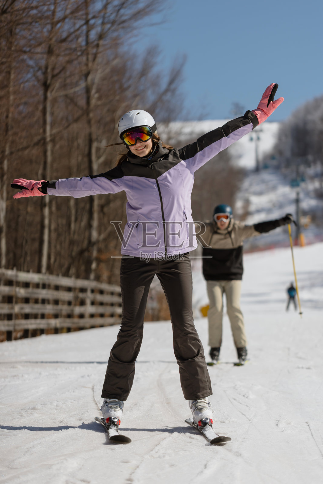 一名女子在雪坡上开心庆祝滑雪日,并举起双手照片摄影图片
