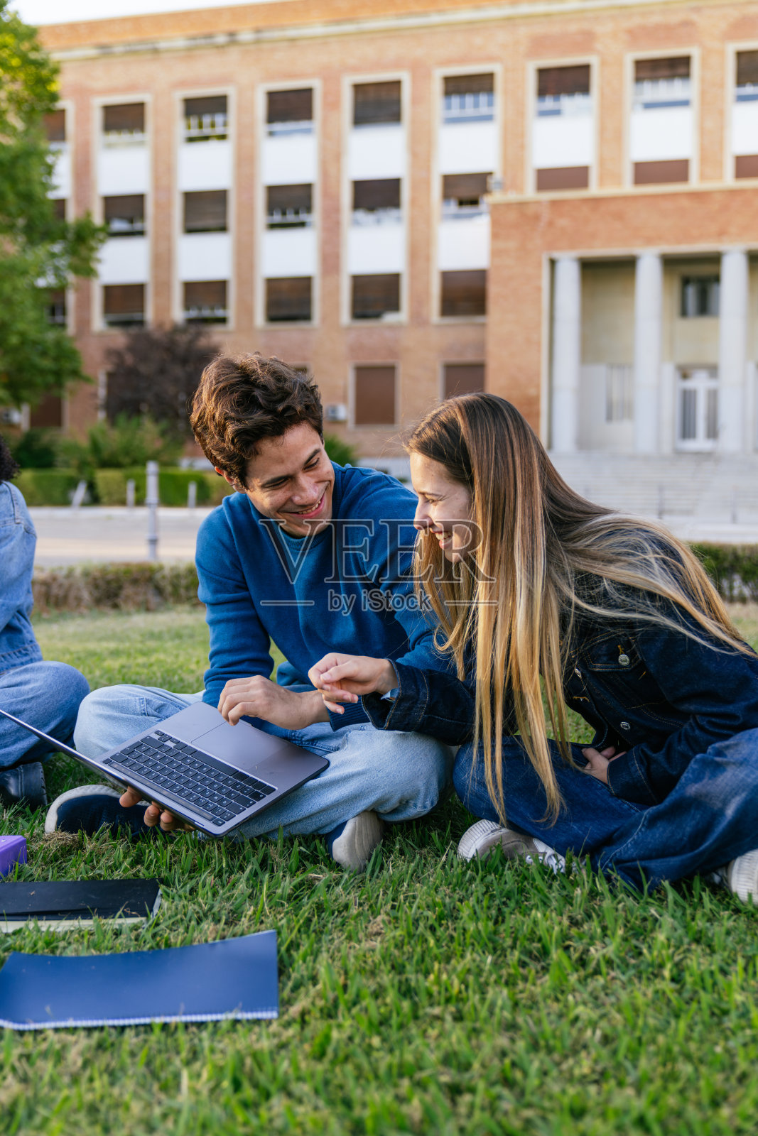 学生们在校园草地上看着笔记本电脑开心地笑照片摄影图片
