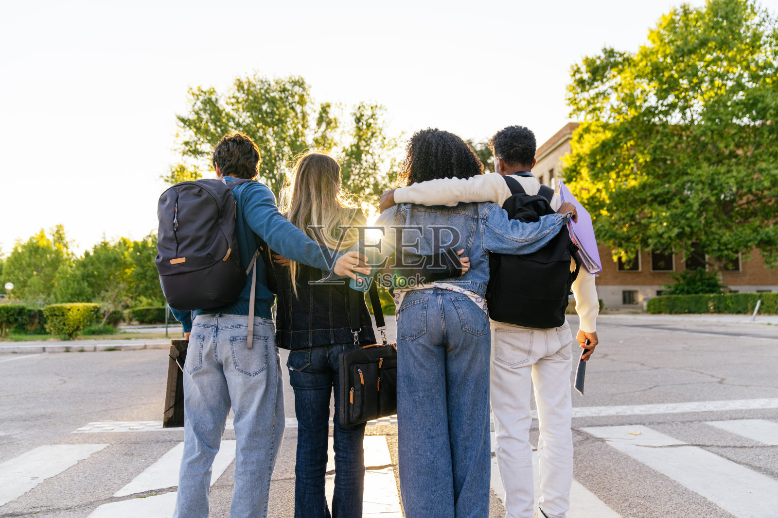 夕阳下,多元化的学生们在大学校园里一起行走照片摄影图片