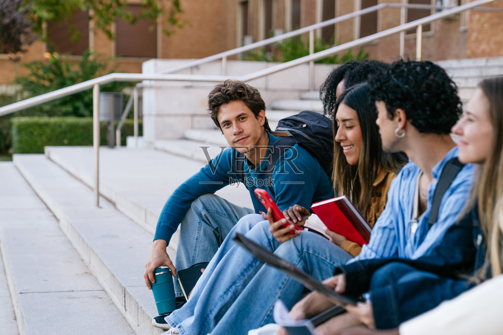 一群不同种族的学生坐在大学校园的楼梯上照片摄影图片