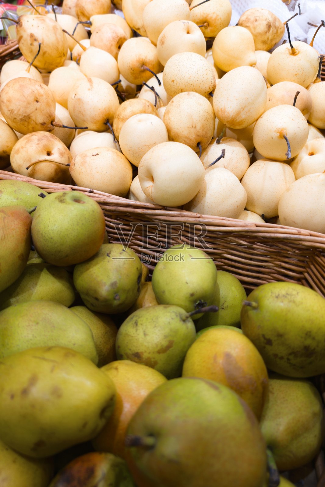 阳光明媚的日子里,市场上摆放着装在篮子里的新鲜梨照片摄影图片