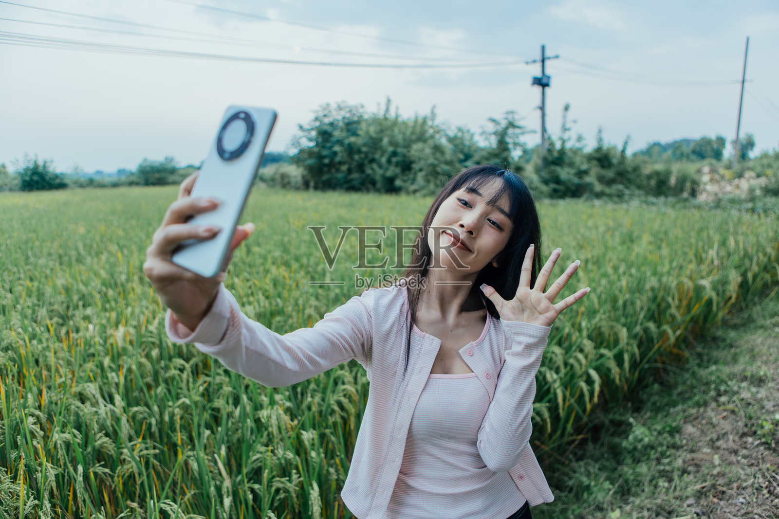 年轻亚洲女性在乡村道路上用智能手机自拍,享受乡村旅行,同时连接社交媒体,展现现代数字生活方式。照片摄影图片