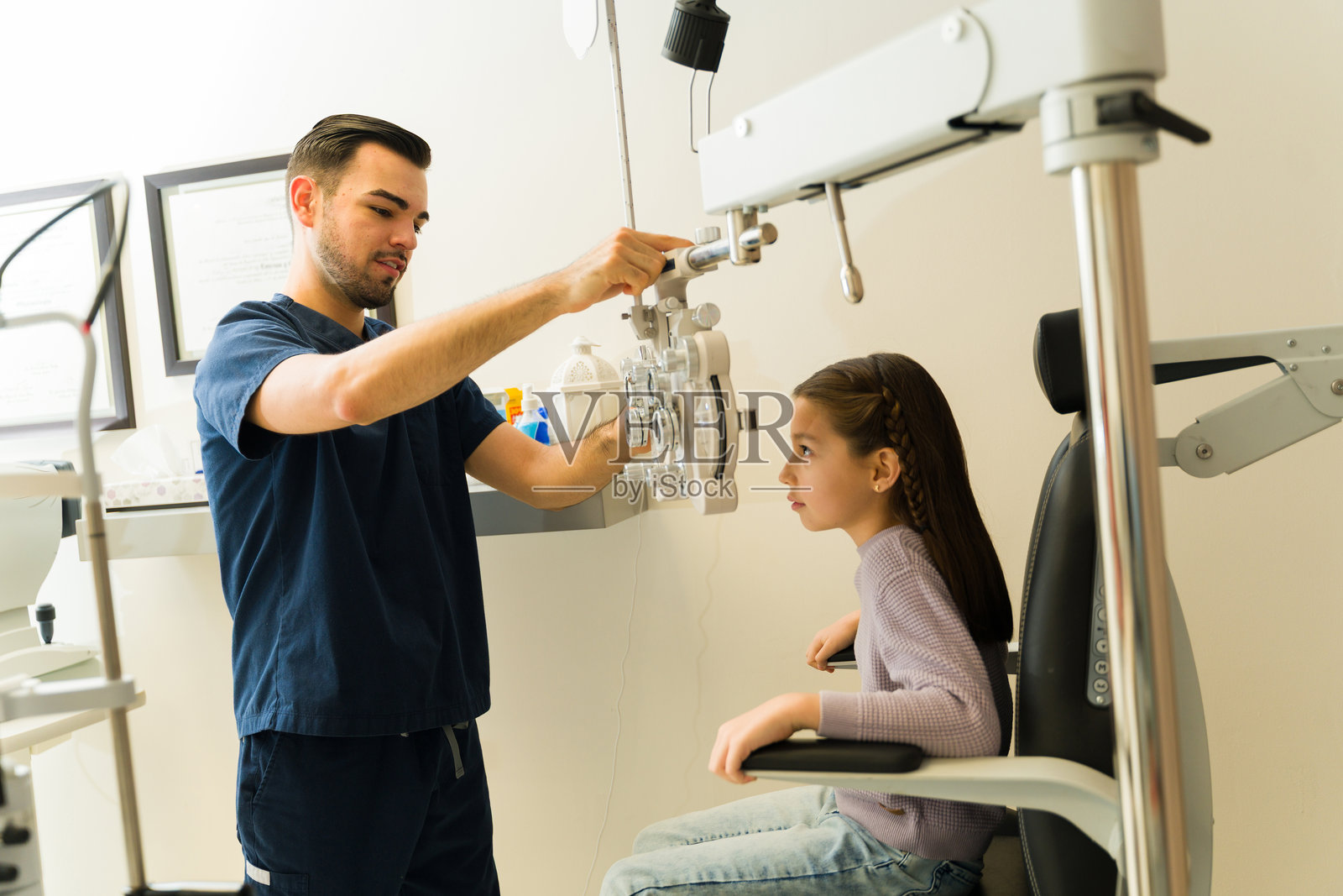 拉丁裔验光师使用专业设备检查儿童视力,确保眼睛健康并开出适当的视力矫正处方。照片摄影图片