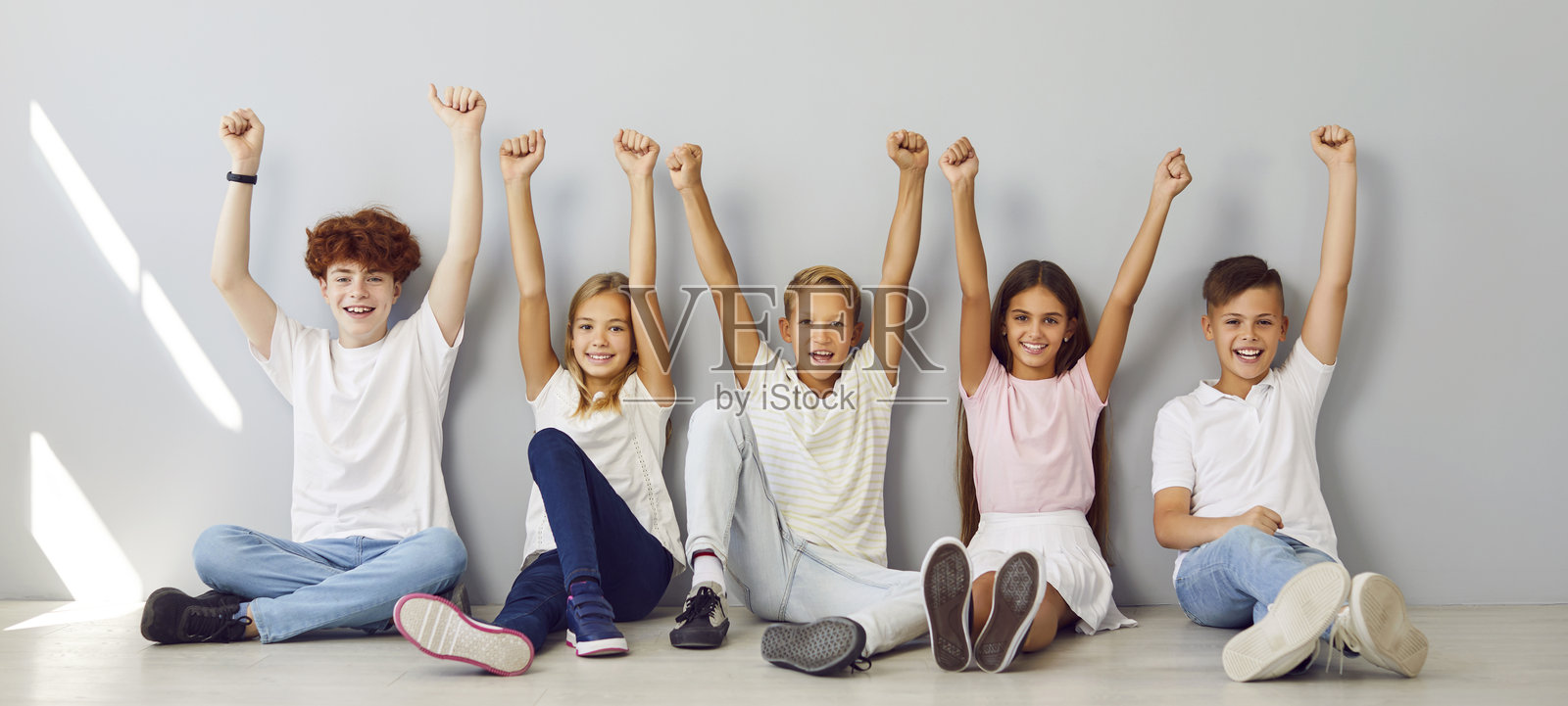 一群来自不同背景的孩子在灰色背景上手举起手照片摄影图片