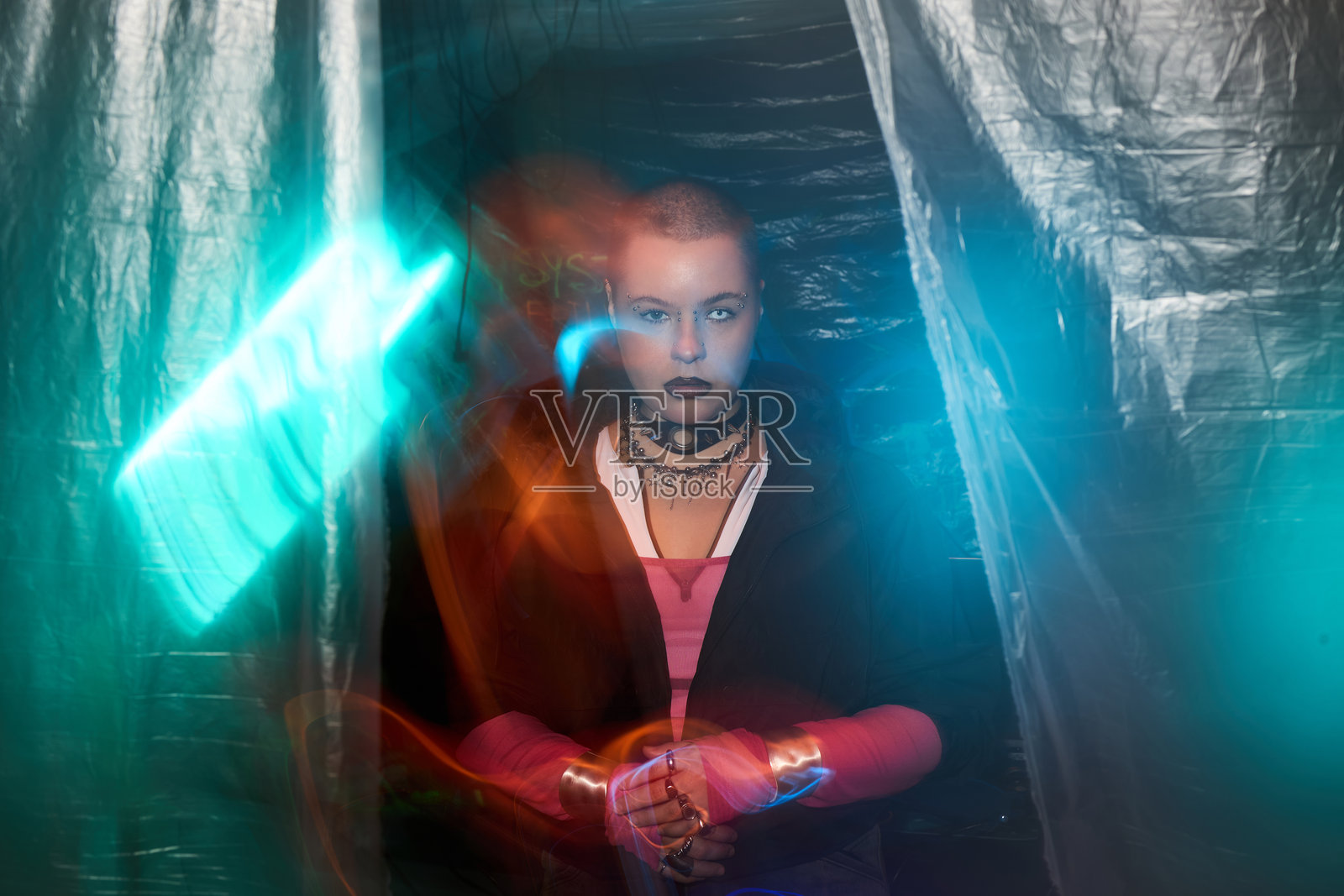 霓虹灯下,年轻的赛博朋克女性站在塑料薄膜中,肖像照照片摄影图片