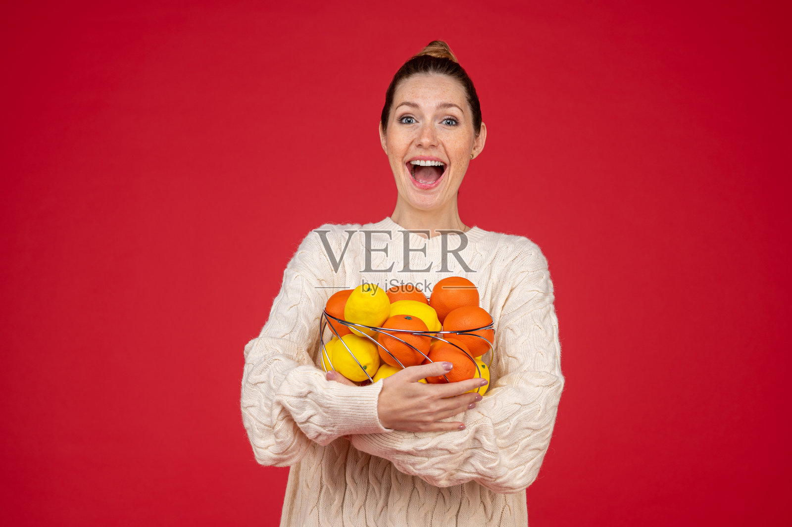 一位年轻女子手持水果,面带微笑,看起来很开心照片摄影图片