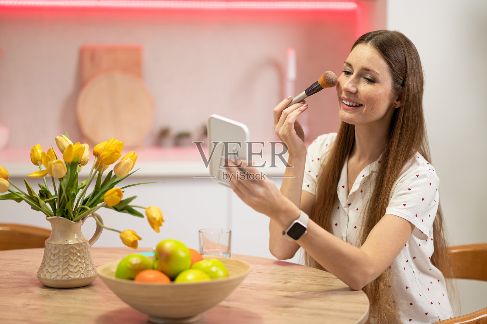 留着长发的年轻美女坐在桌前,手中拿着一把面部刷照片摄影图片