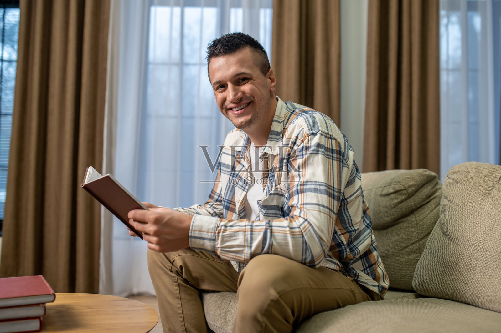 男人微笑着坐在沙发上阅读照片摄影图片