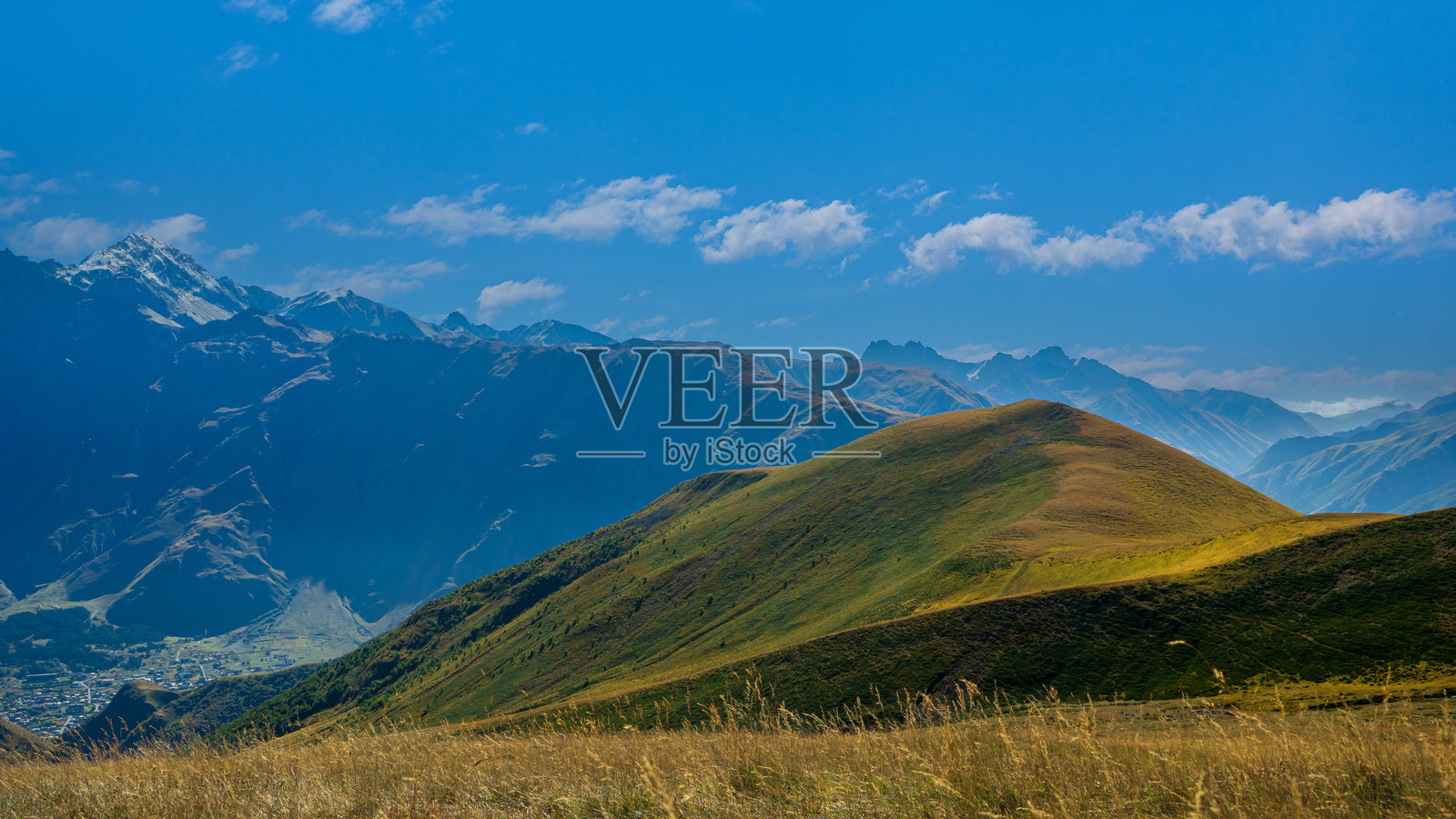 晴朗的阳光下,绿色山脊,背景是壮丽的蓝色山脉。照片摄影图片