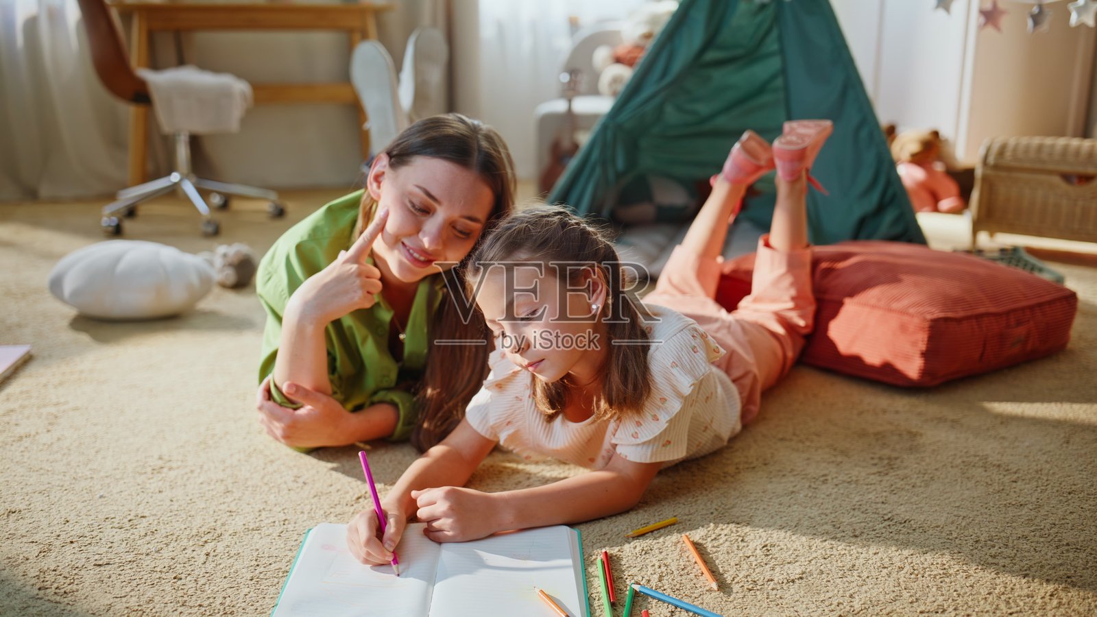 母女俩在阳光明媚的房间里共度时光。幸福的一家在绘画。照片摄影图片