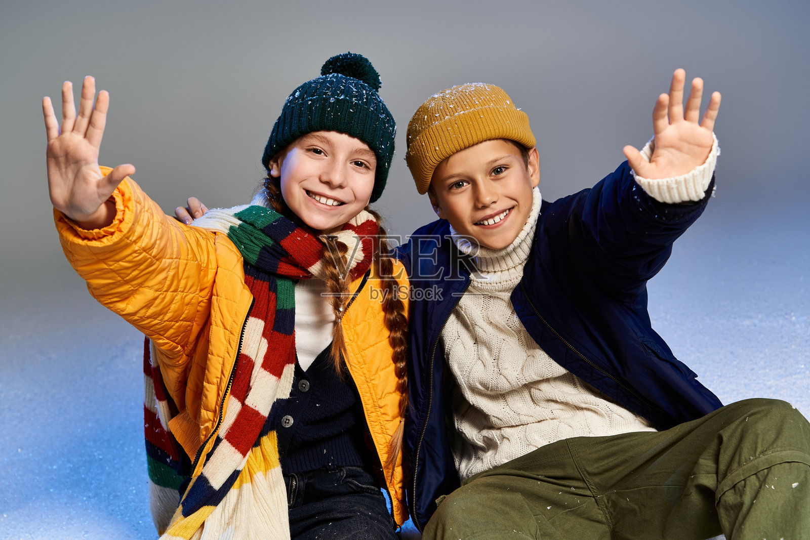 两个快乐的孩子穿着色彩鲜艳的保暖服装,享受着冬天的乐趣照片摄影图片