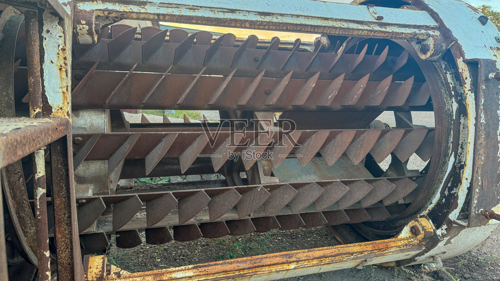 一个风化圆柱形外壳内的带叶片的大型工业生锈金属转子。照片摄影图片