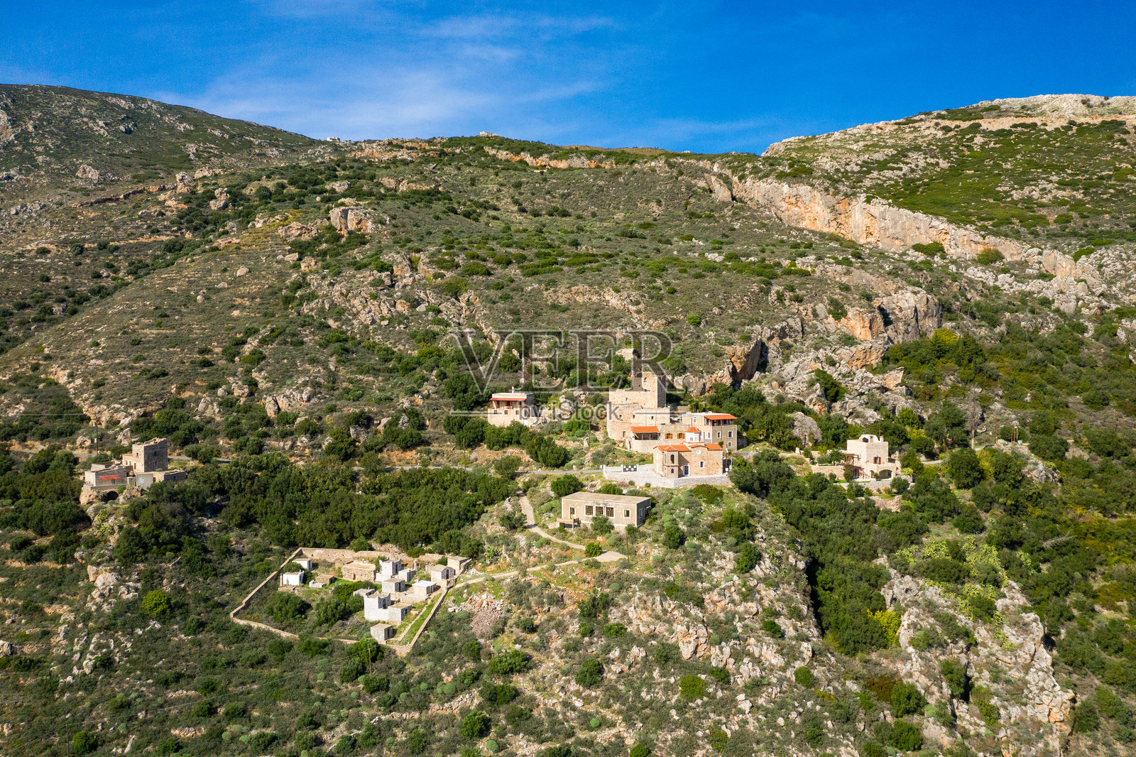 散落在绿色马尼山坡上的石屋照片摄影图片
