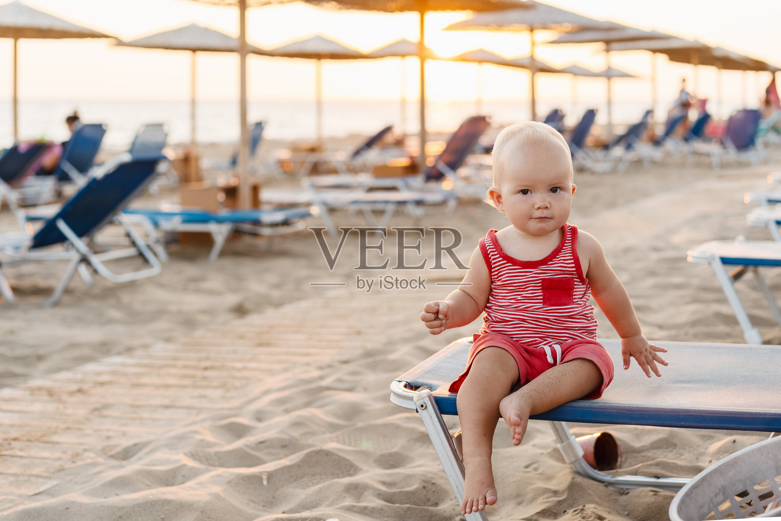 微笑的婴儿在海边爬行玩耍。快乐的小孩在海边玩耍。照片摄影图片