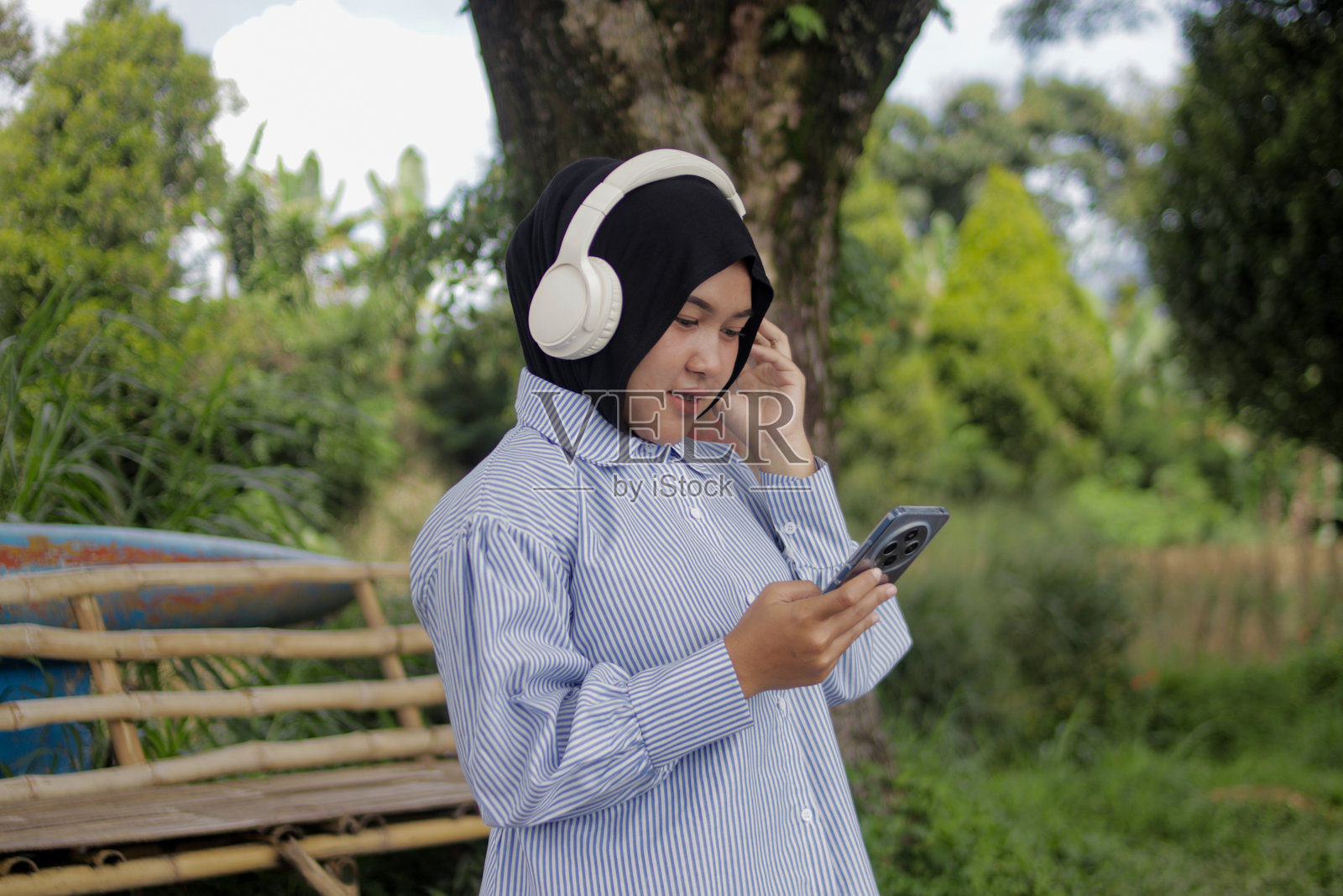 一位年轻的亚洲穆斯林女性在户外戴着无线耳机享受音乐照片摄影图片