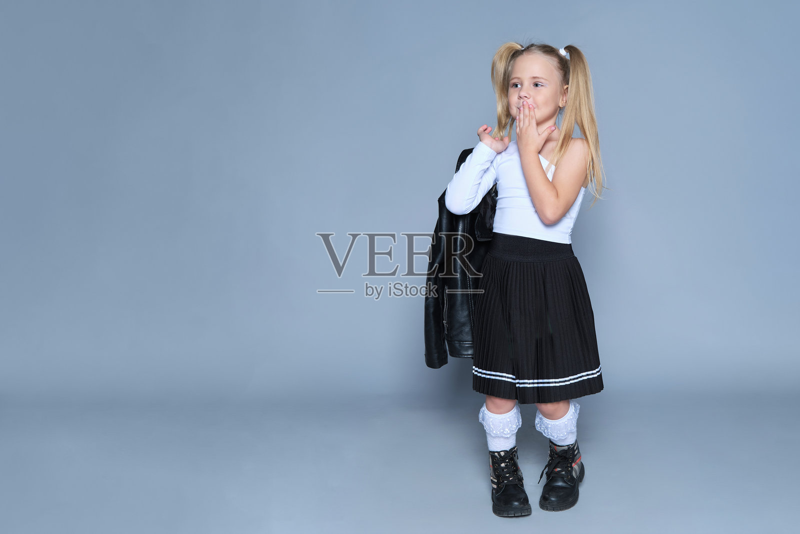 这位时尚的女学生将经典与前卫风格融为一体,身穿黑色百褶裙和蕾丝袜,搭配皮夹克。她自信的姿势为返校主题增添了俏皮感,非常适合儿童时尚推广。照片摄影图片