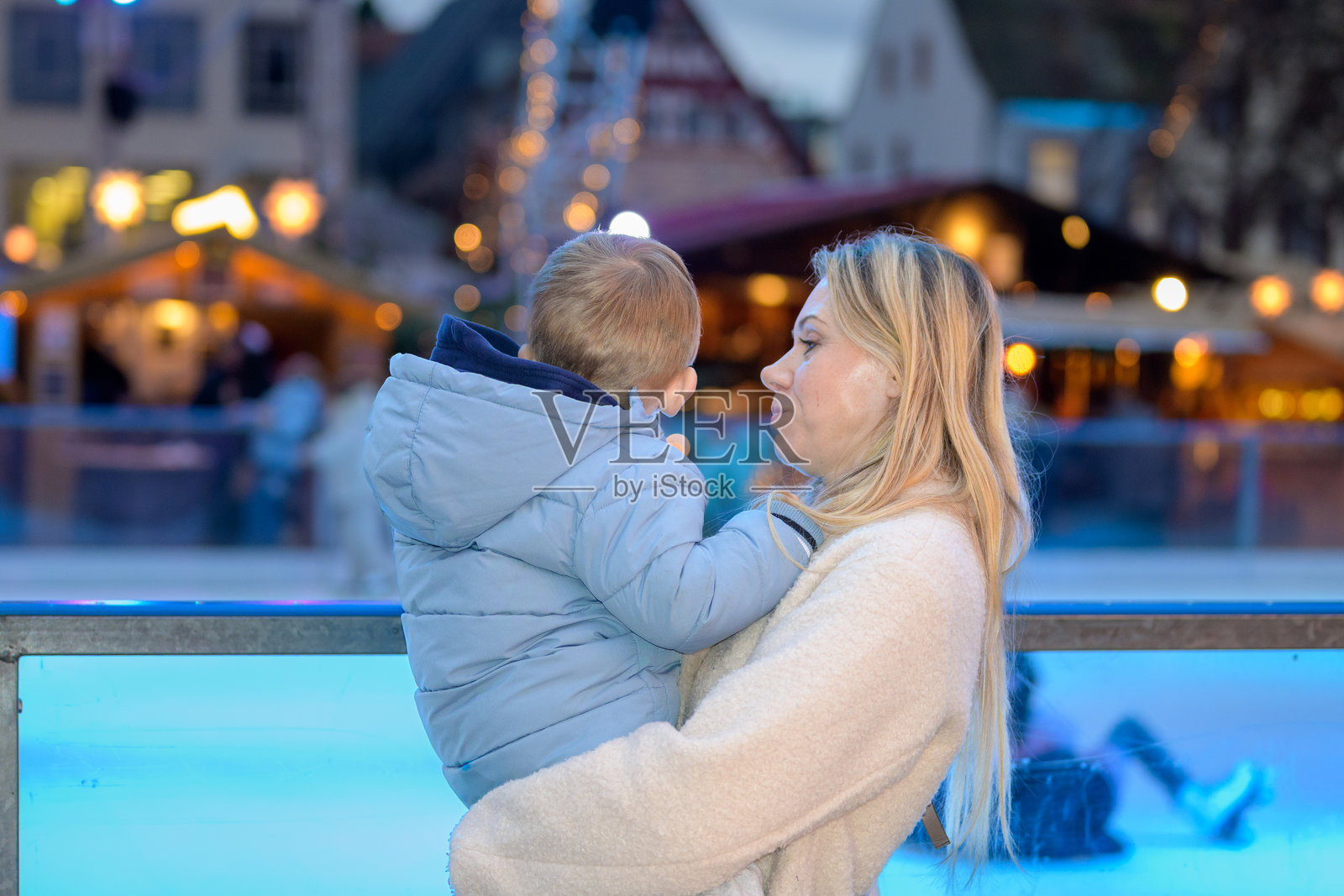 母亲在圣诞集市抱着孩子照片摄影图片