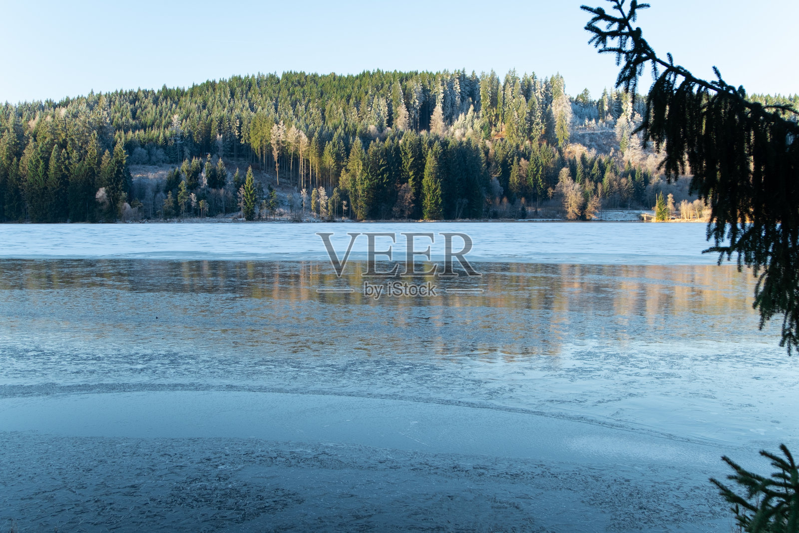 冰封的冬季湖泊,周围环绕着森林山丘,湖面结冰照片摄影图片
