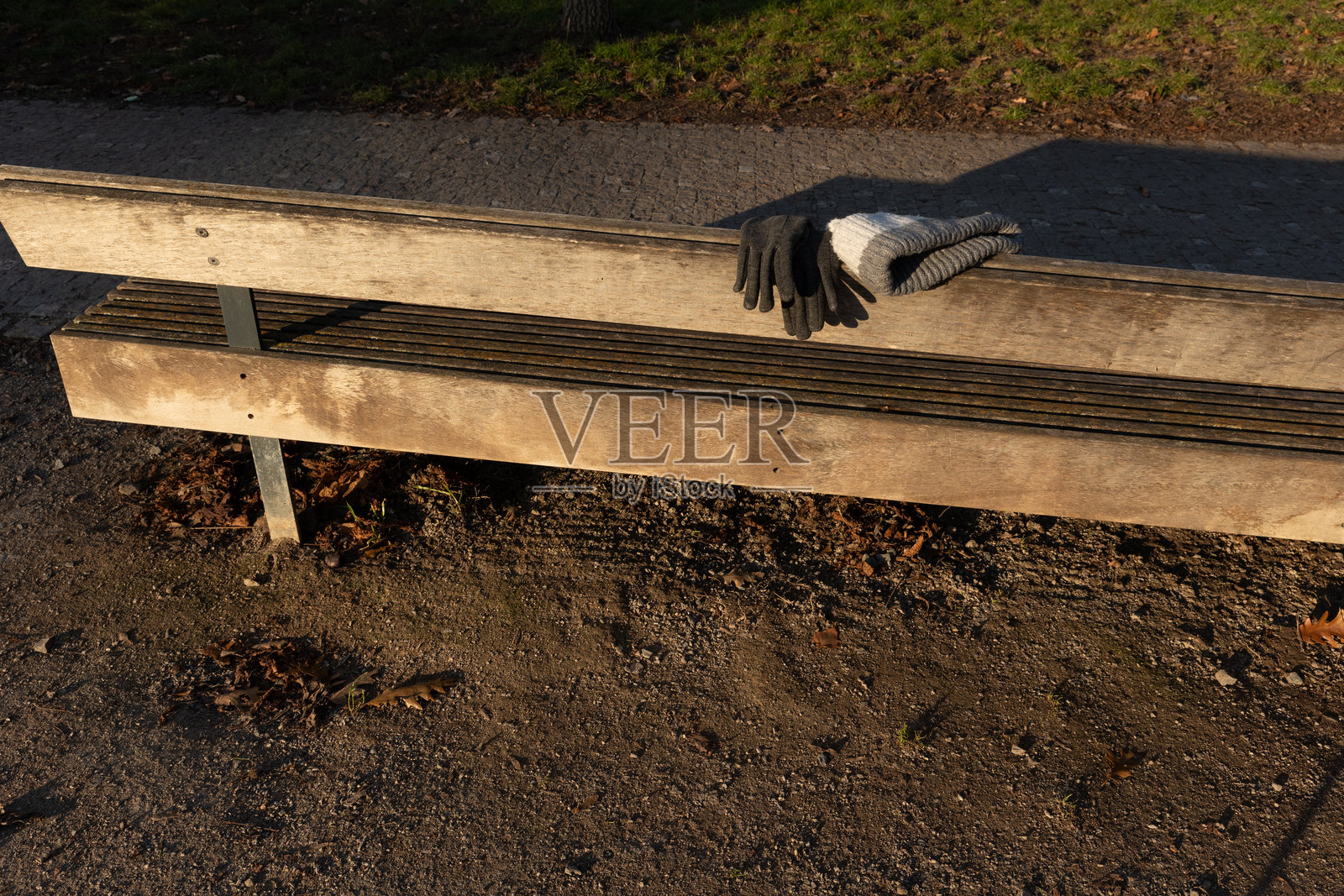 木质公园长凳上遗失的手套和冬季帽子照片摄影图片