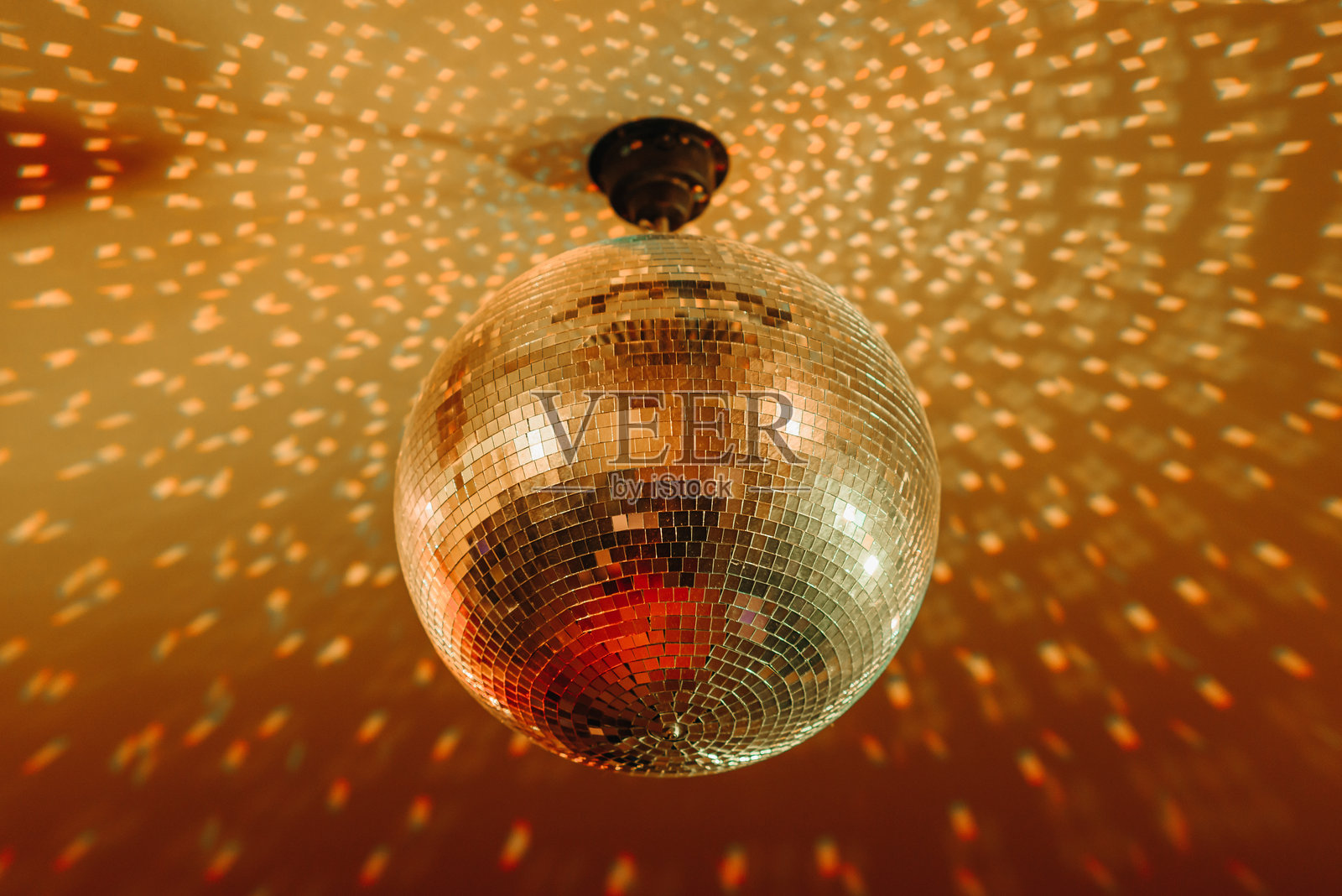 带有镜面和明亮光线的迪斯科球,橙色,悬挂在天花板上,夜间派对背景照片摄影图片
