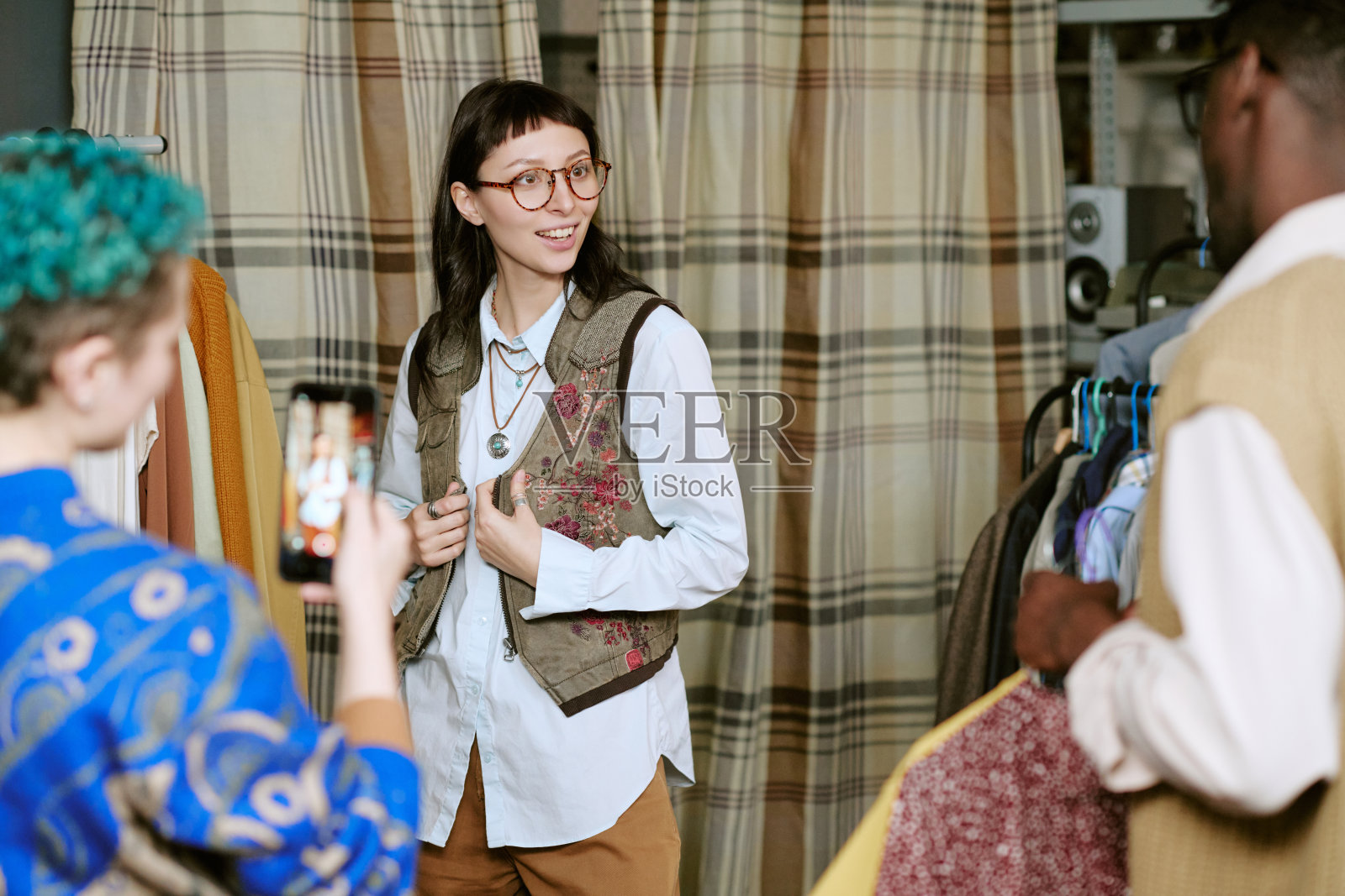 年轻的高加索女性在试穿二手背心,并对着朋友微笑照片摄影图片