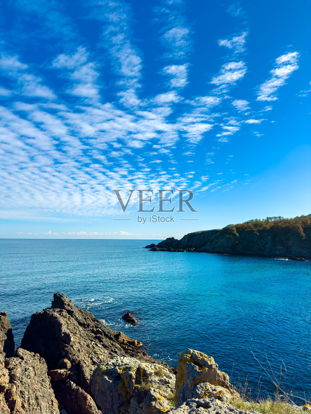 岩石海岸在中午时分,可以看到海岸线和海洋,背景是晴朗的天空和云彩照片摄影图片