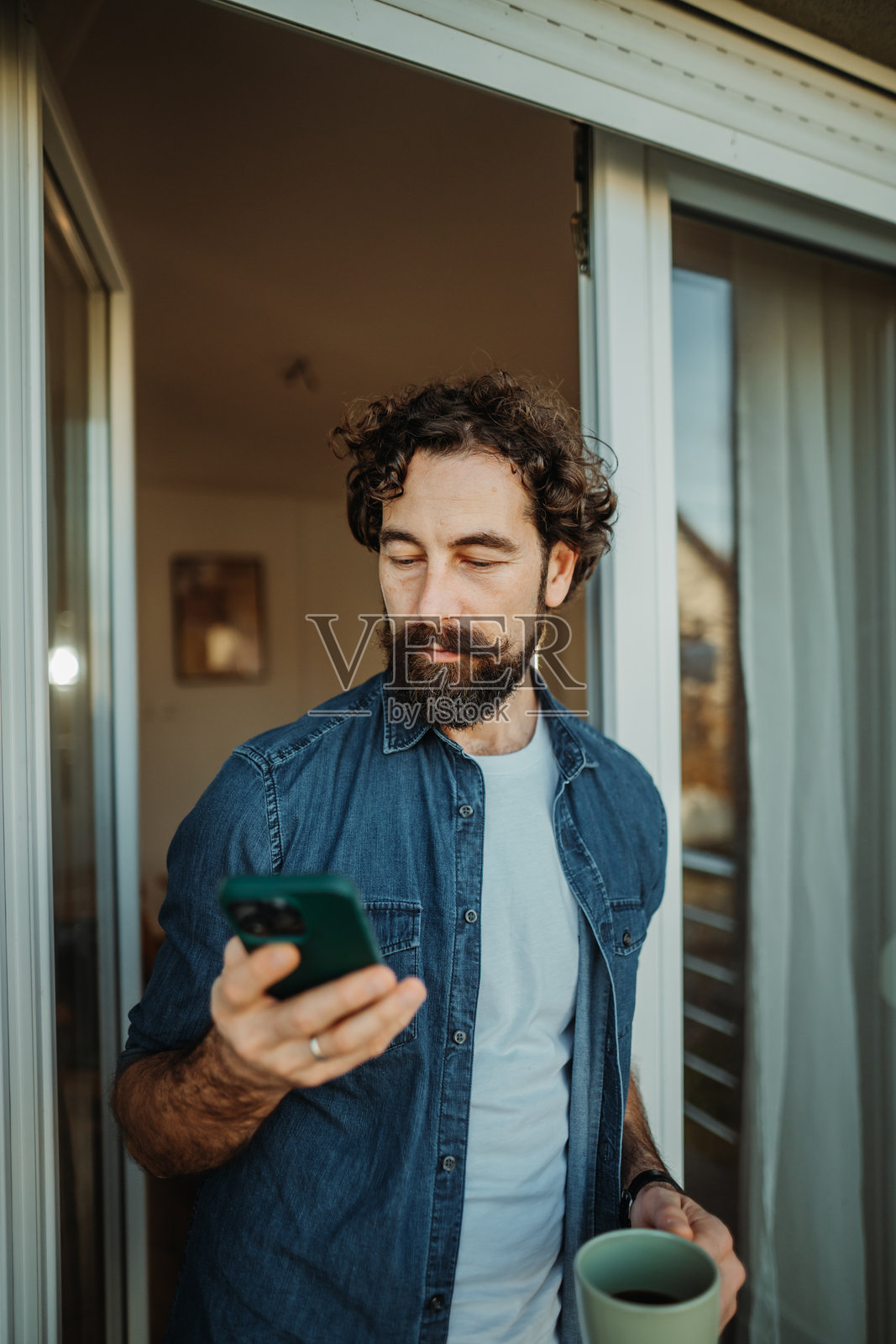 年轻男子在阳台上查看智能手机照片摄影图片