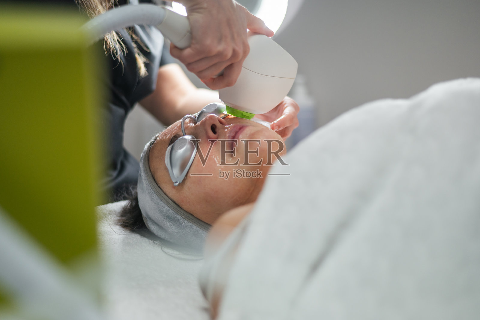 美容师在顾客脸上进行激光嫩肤治疗照片摄影图片