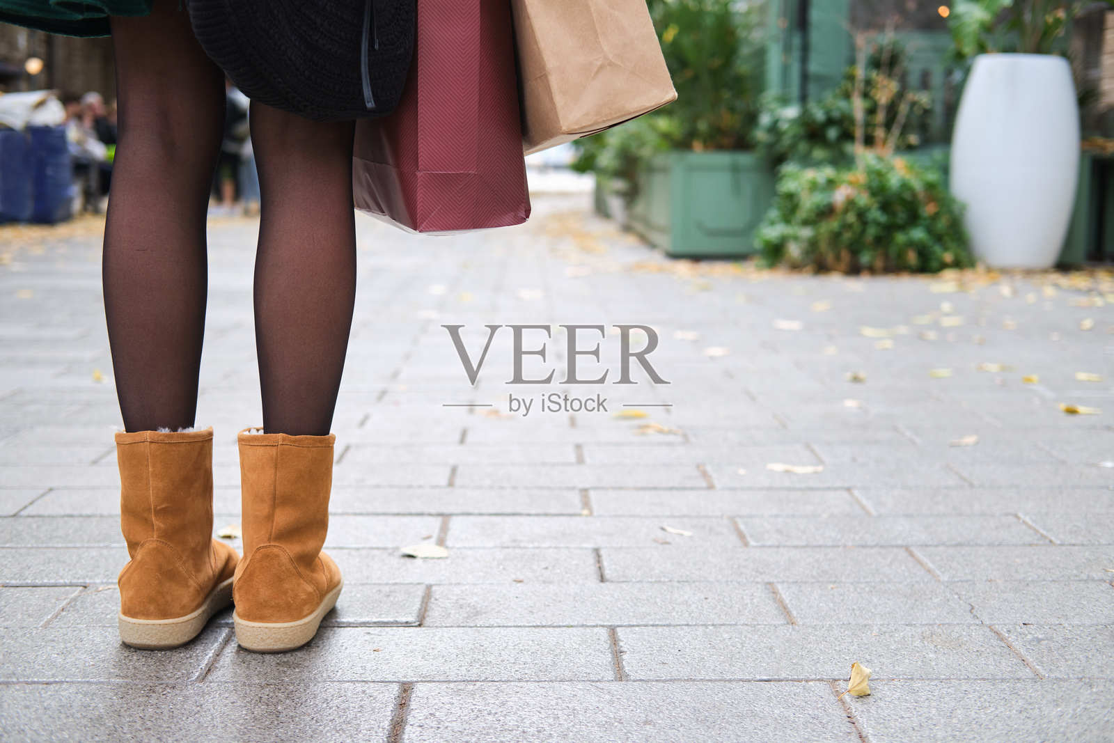 一名女子站在街上,手提购物袋,角度特写,人物身份无法辨认照片摄影图片