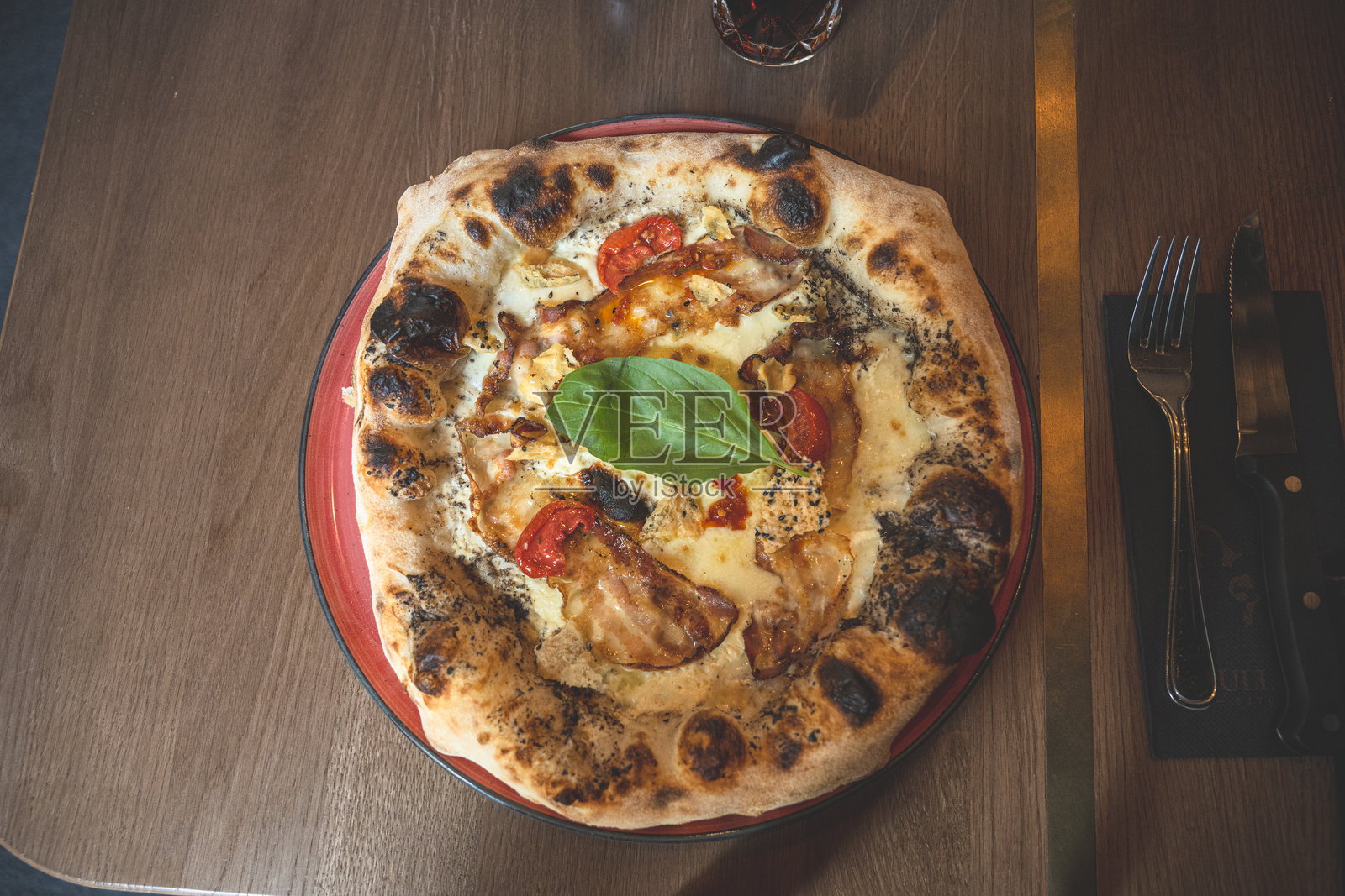 用柴火烤制的美味披萨,配有融化的奶酪和新鲜罗勒。照片摄影图片