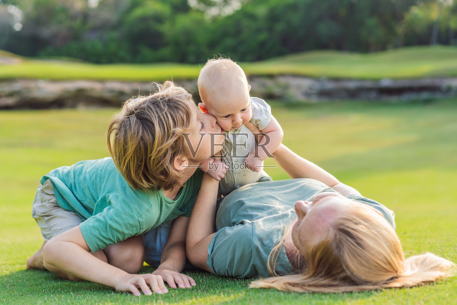 母亲、大儿子和新生儿在公园的草地上。一家人在大自然中享受亲子时光。育儿、爱与家庭纽带的概念照片摄影图片