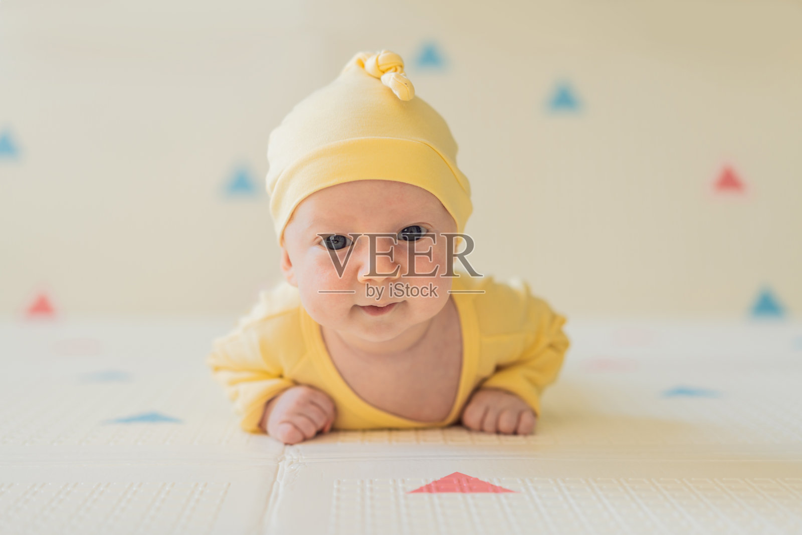 一个月大的婴儿趴着,好奇地观察周围。婴儿俯卧抬头练习,以增强颈部力量、认知发展和早期探索。育儿和新生儿成长理念。照片摄影图片